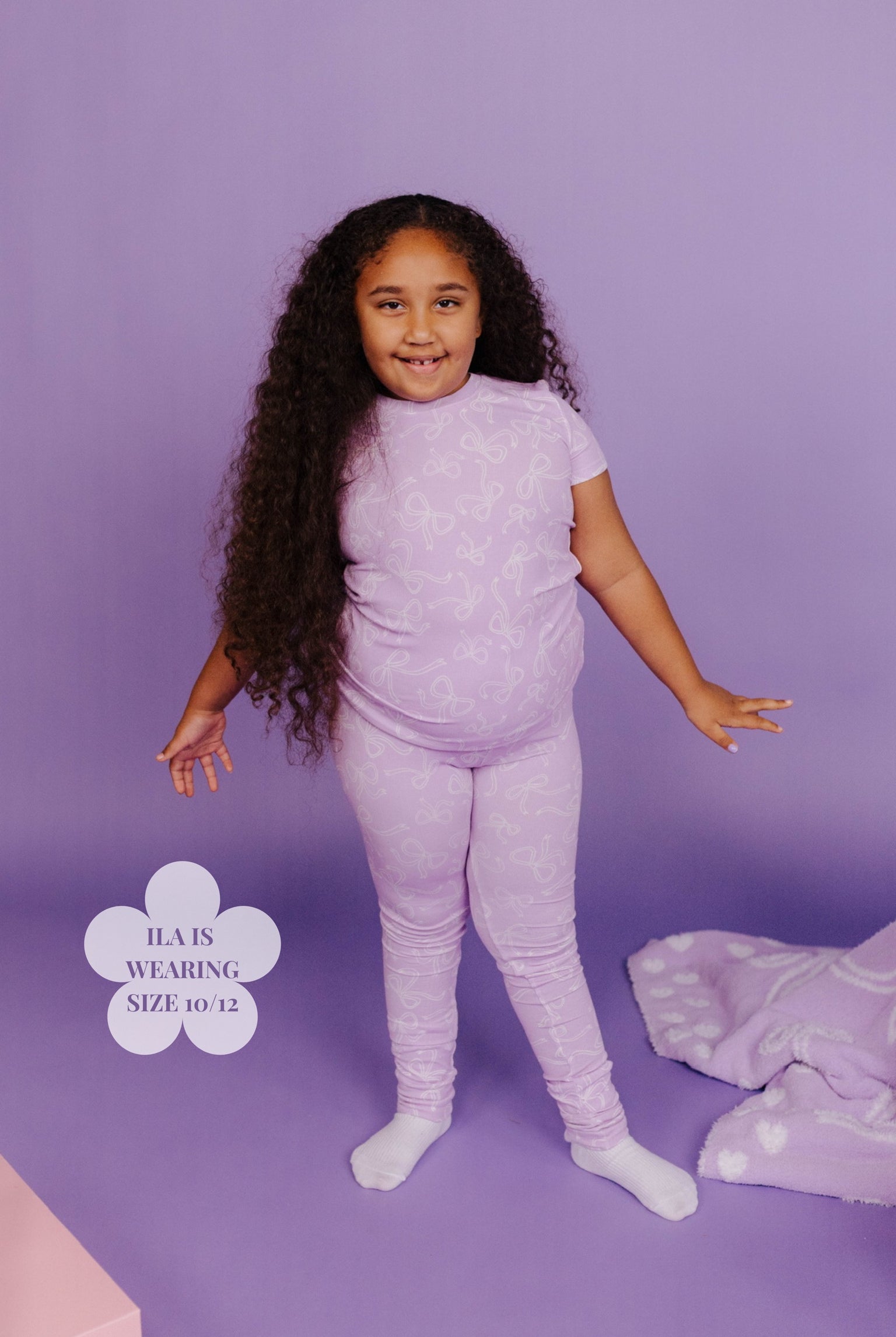 Young girl wearing a matching purple outfit with a soft purple background