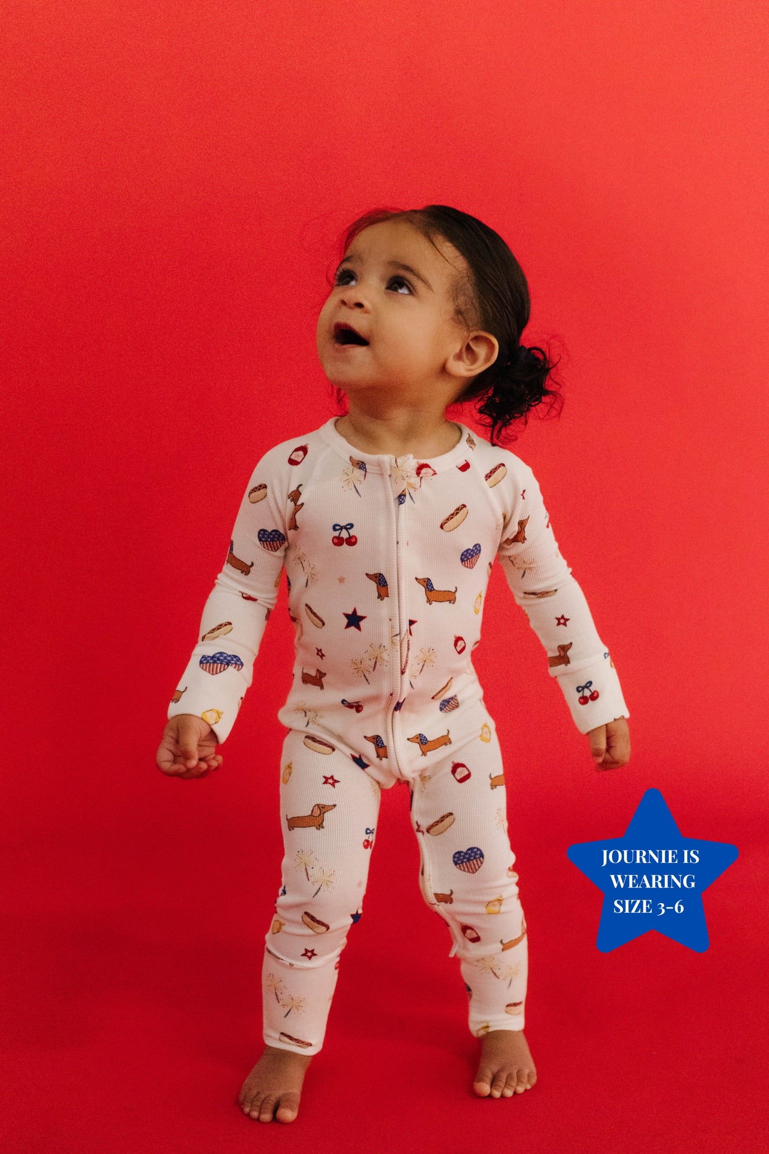 baby standing on red plain background with 4th of july icon print