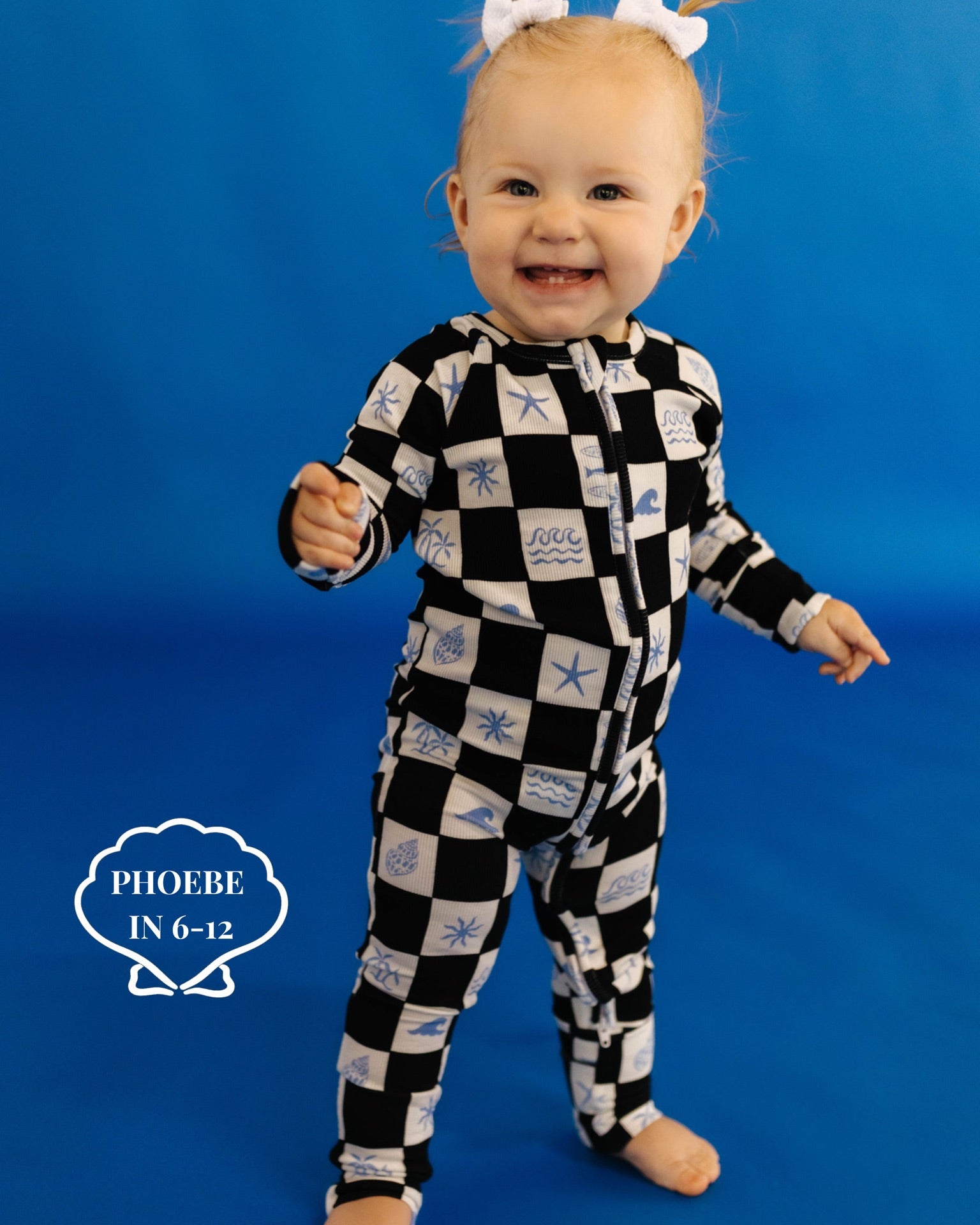 Baby wearing a black and white checkered outfit with shell patterns on a blue background