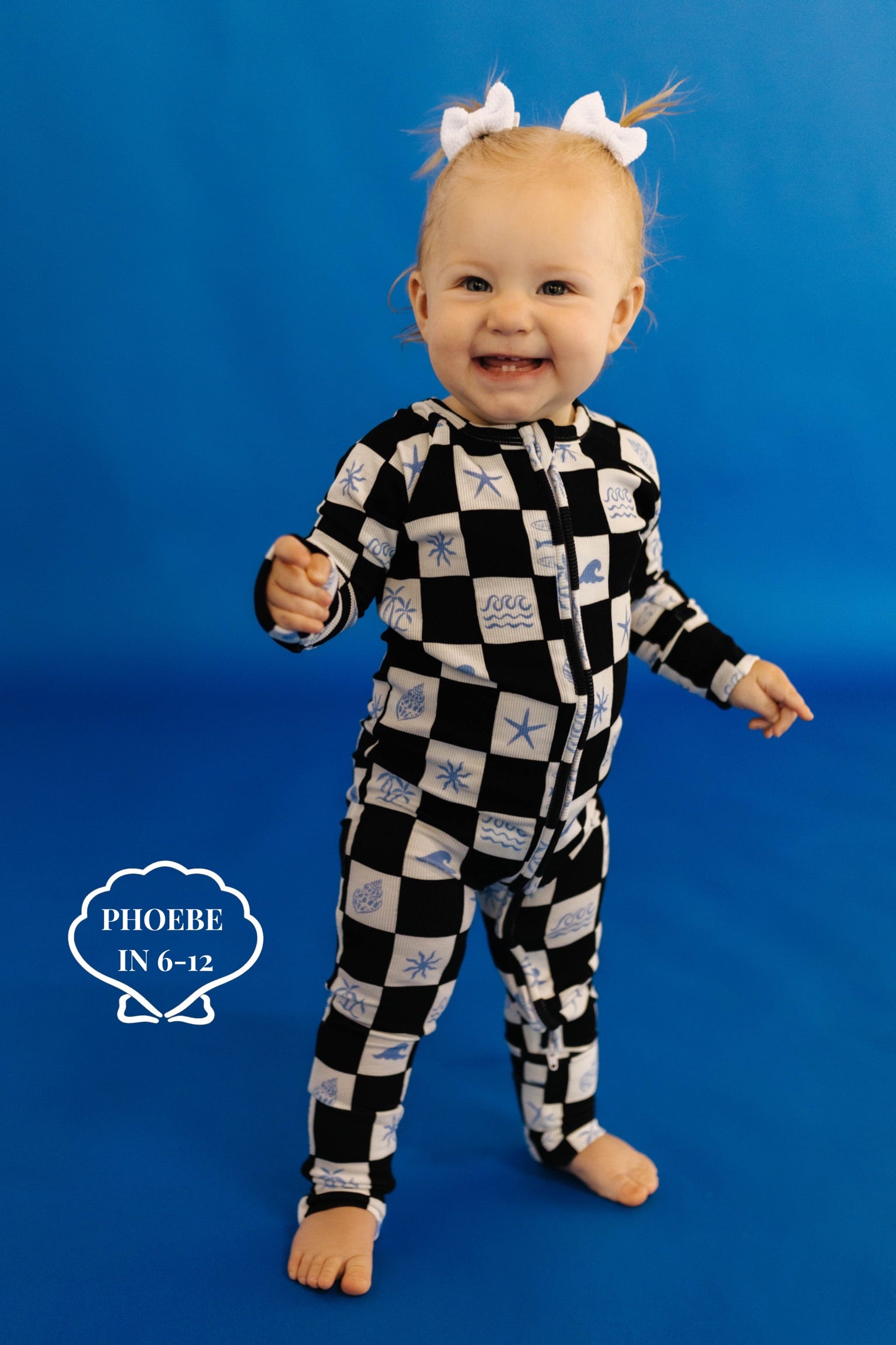 Baby wearing a black and white checkered outfit with shell patterns on a blue background