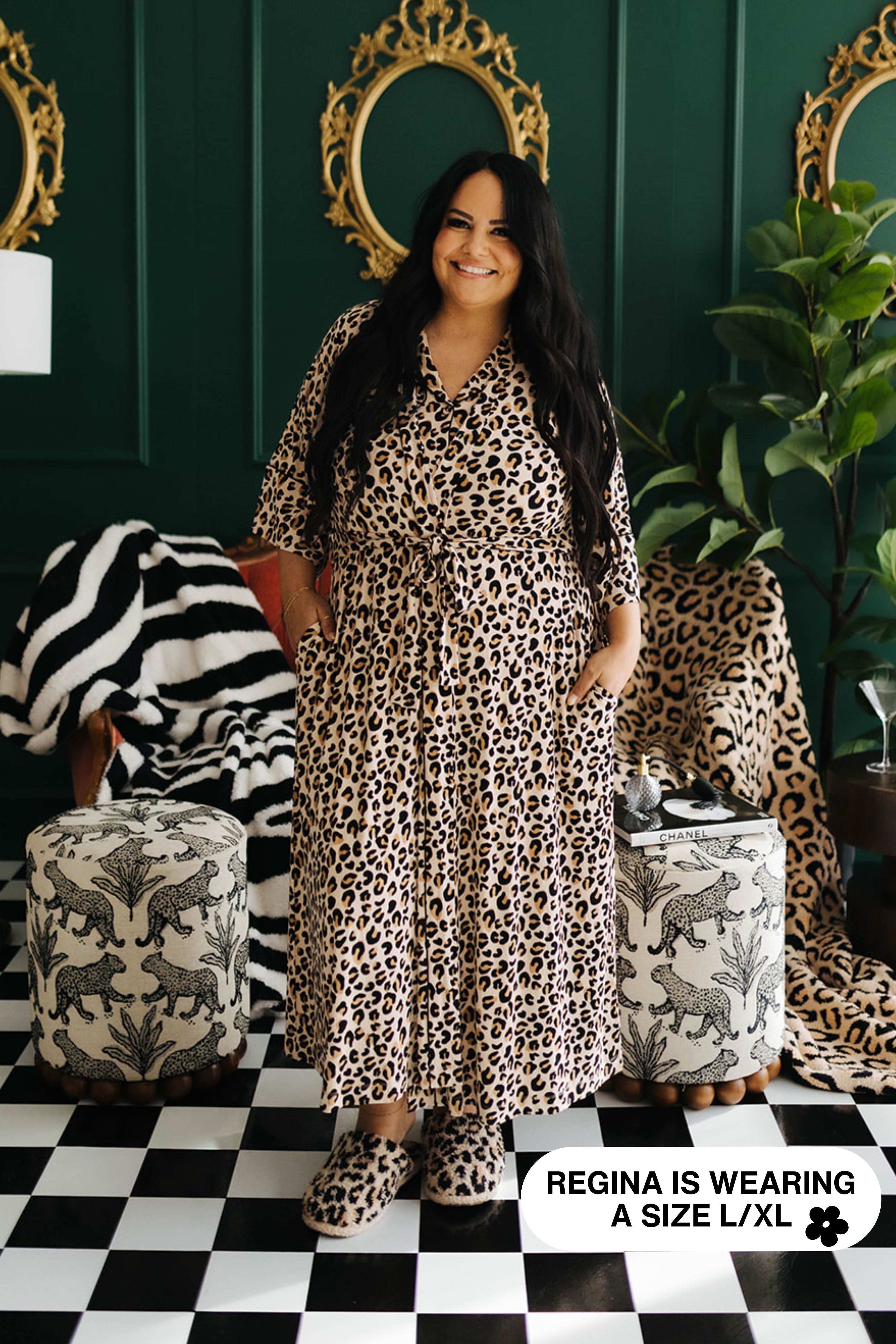 Woman wearing a leopard print doutgit standing in a room with decorative mirrors and furniture.