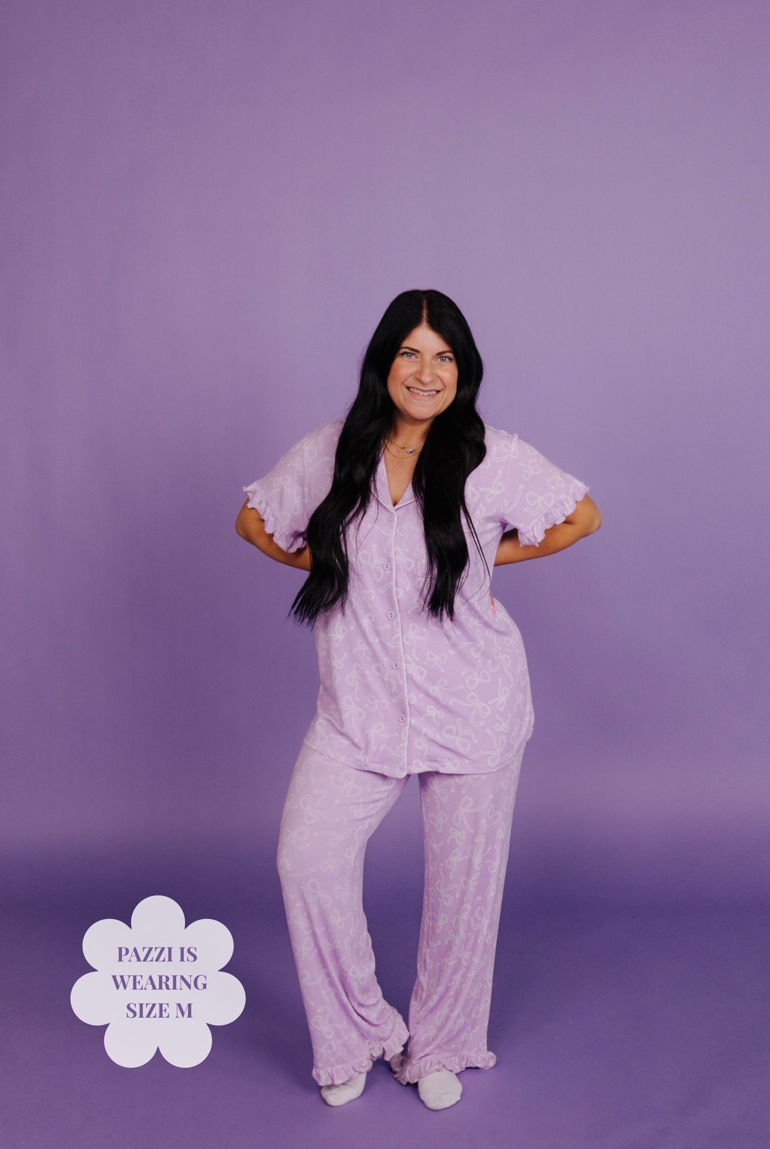 Woman wearing a light purple pajama set against a purple background