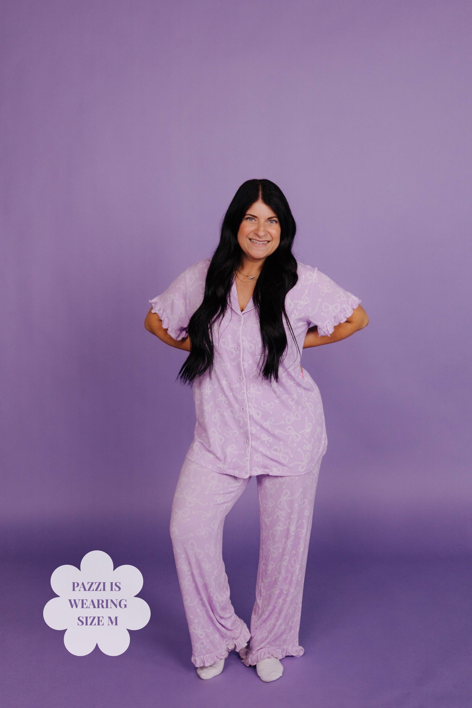 Woman wearing a light purple pajama set against a purple background
