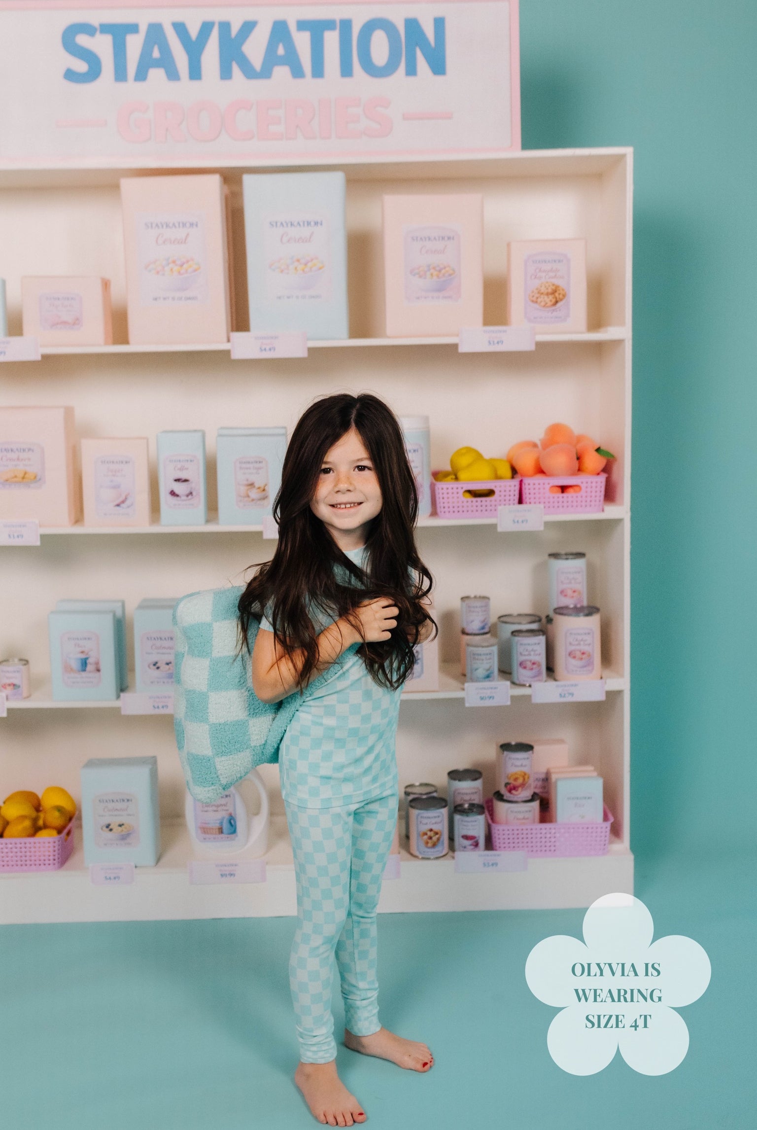 Little girl in teach check pj set with teal check quillow