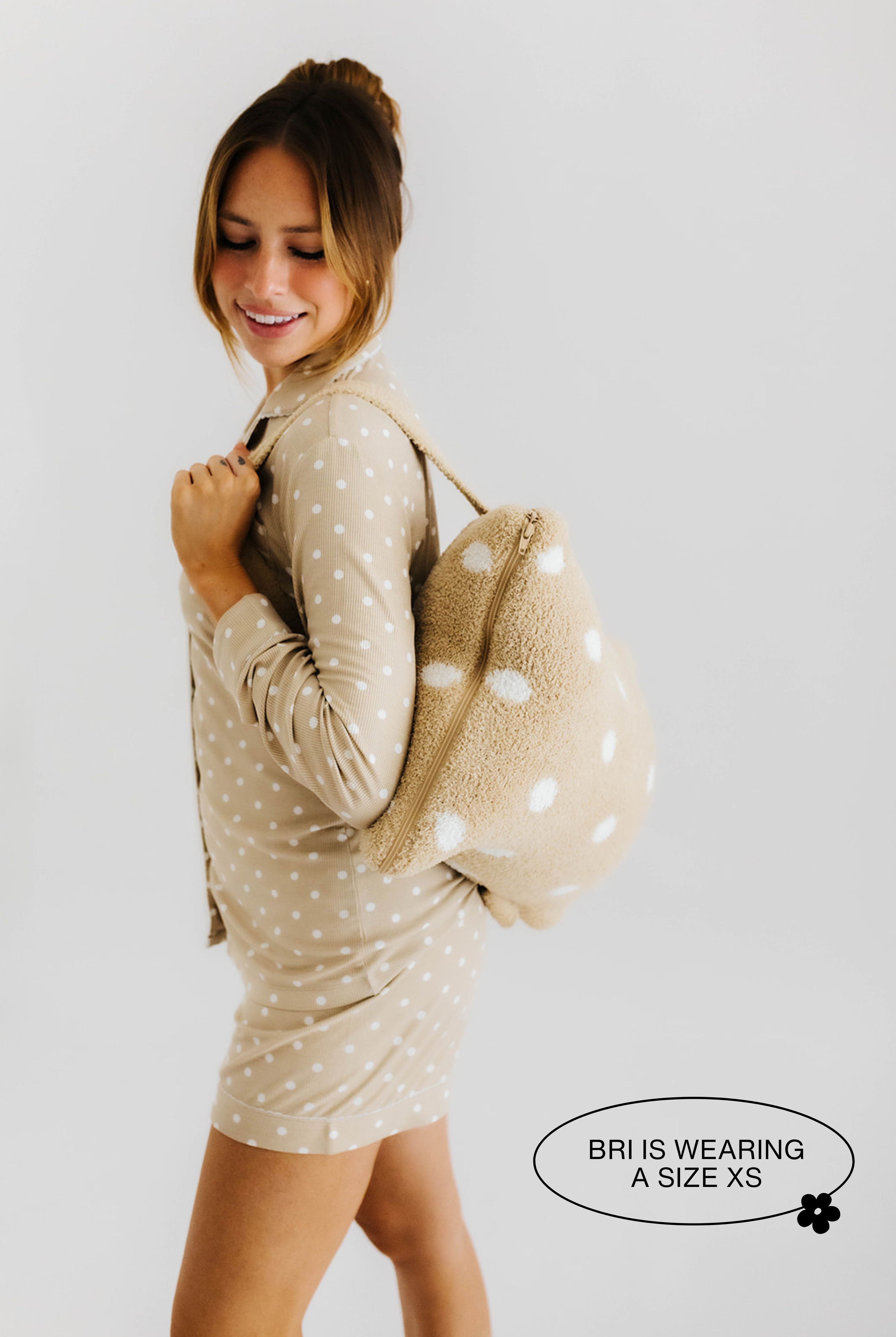 model smiling wearing the polka dot backpack quillow on back