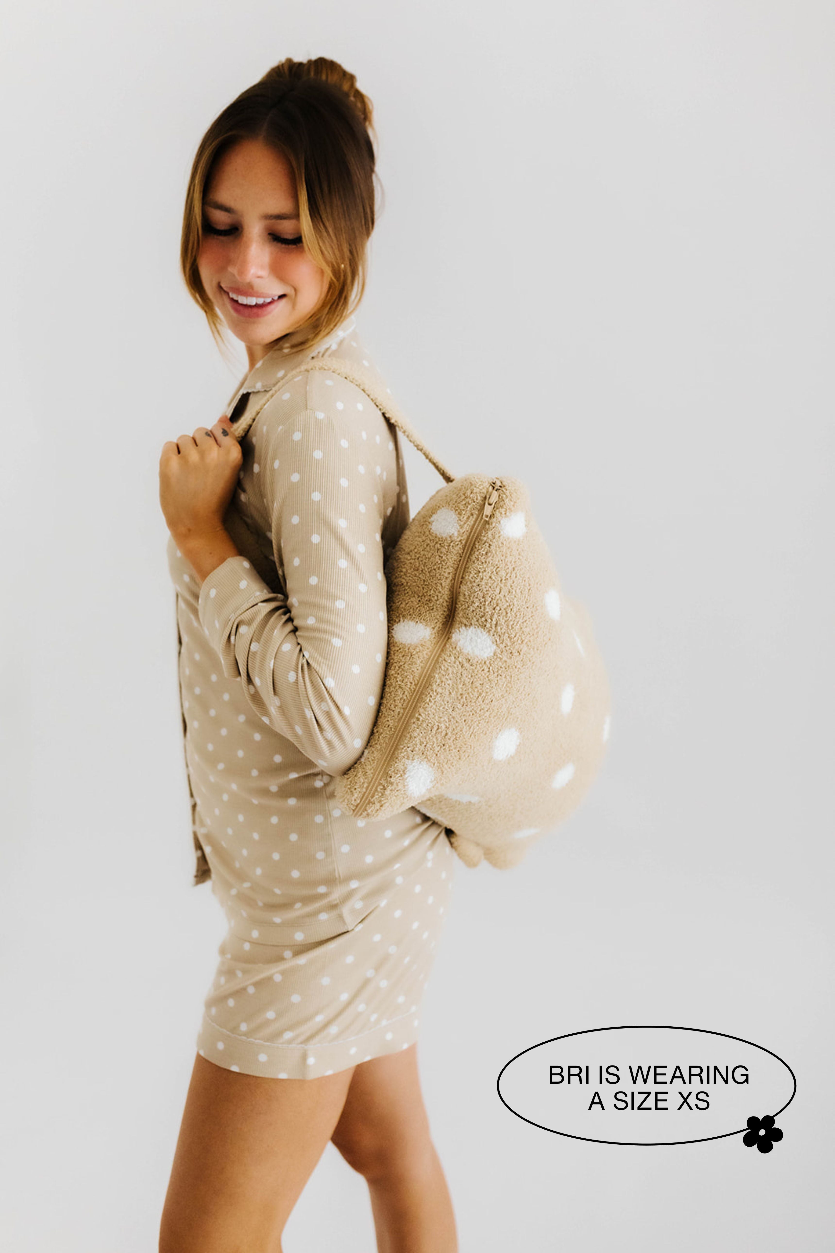 model smiling wearing the polka dot backpack quillow on back
