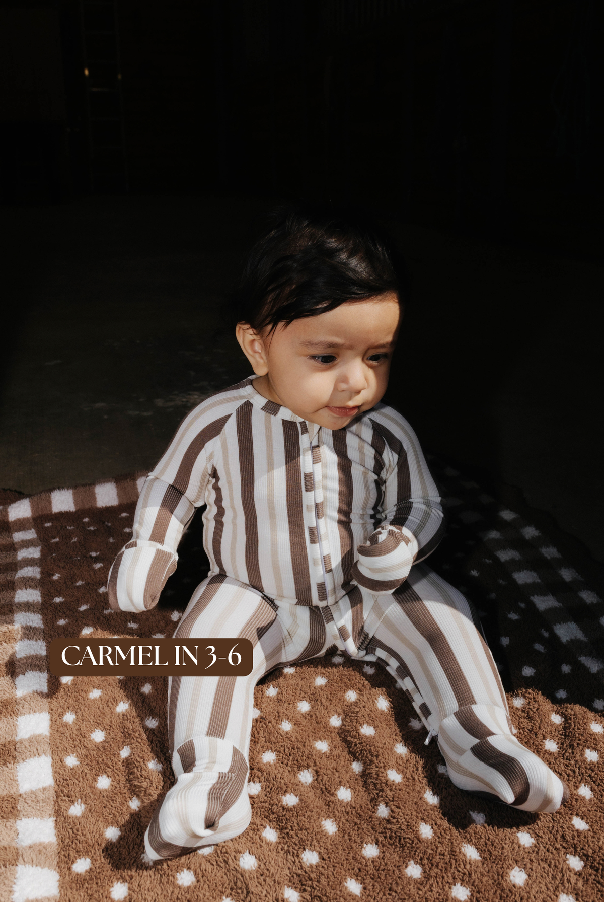 Sizing photo: Carmel in 3-6 months wearing brown and cream striped baby zip pajamas.