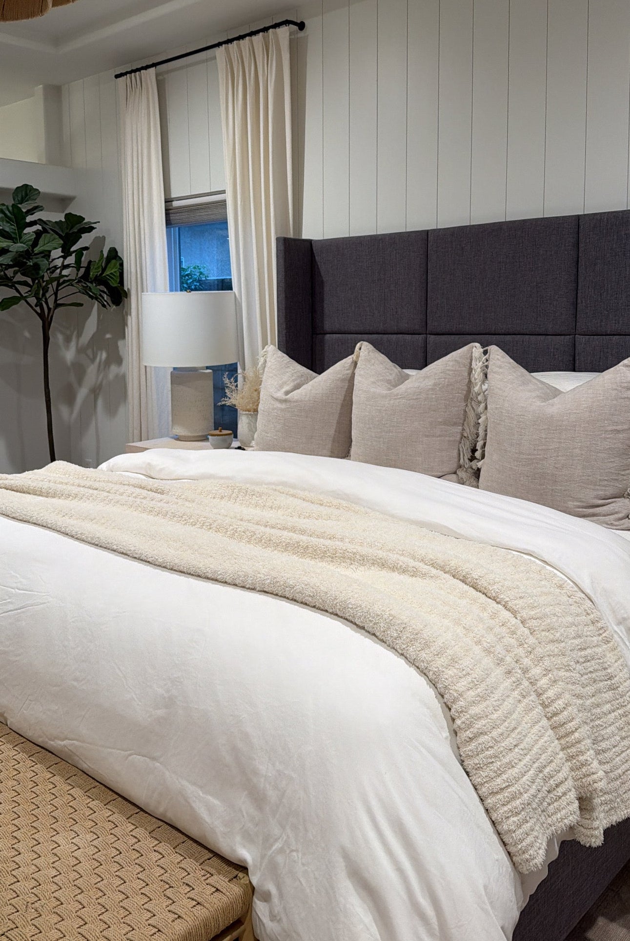 Neatly made bed with white bedding and beige pillows in a bedroom setting.