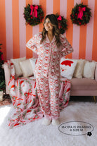 Woman wearing a festive pajama set in a room with Christmas decorations.