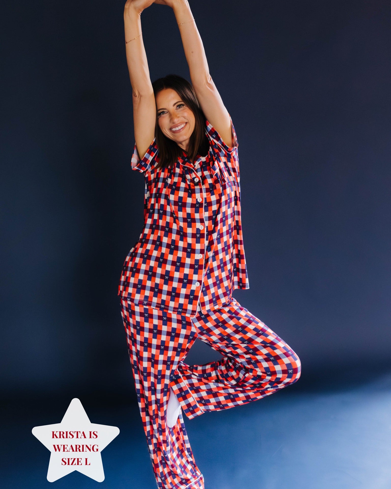 Girl posing wearing a red and blue gingham pj set on blue background