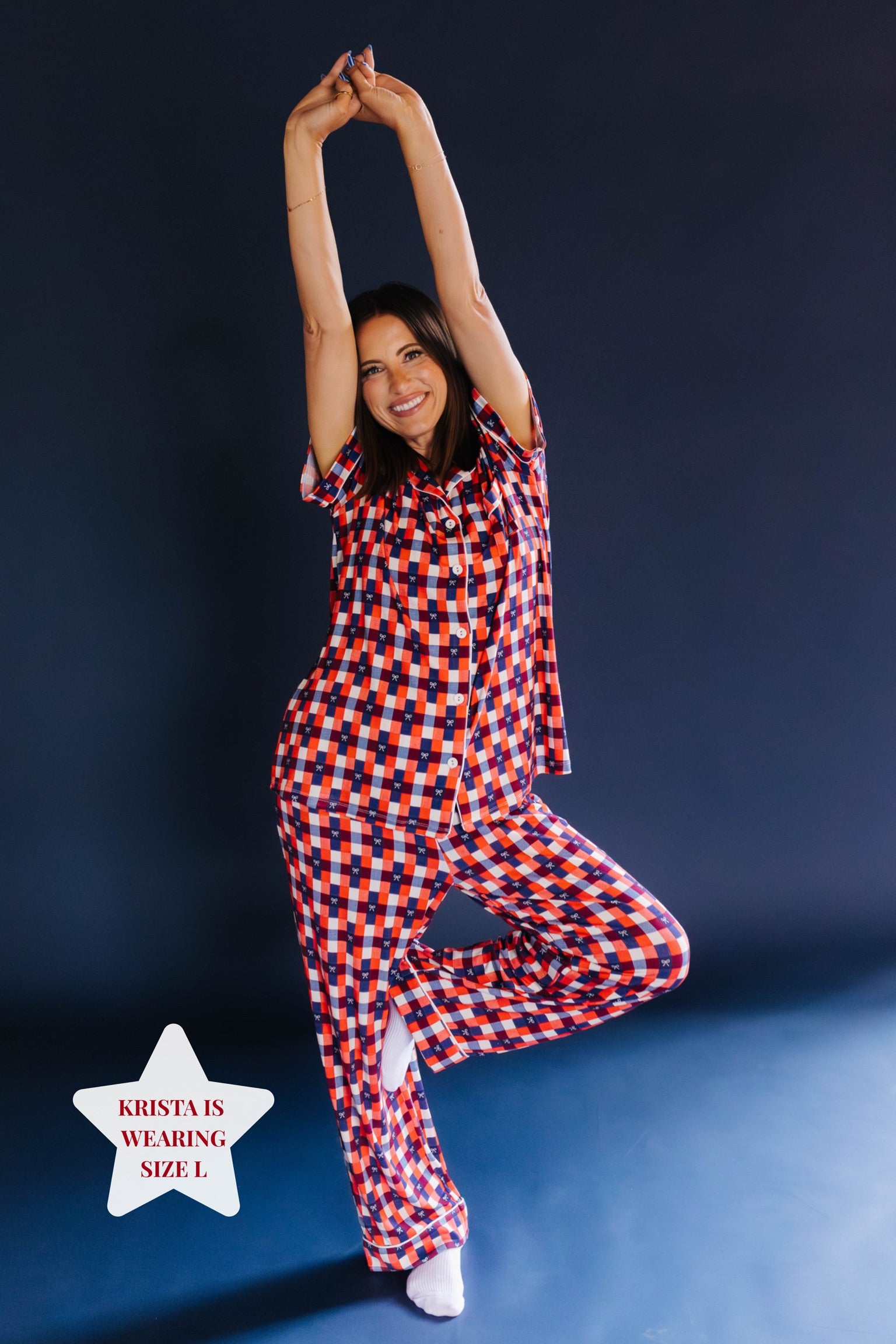 Girl posing wearing a red and blue gingham pj set on blue background
