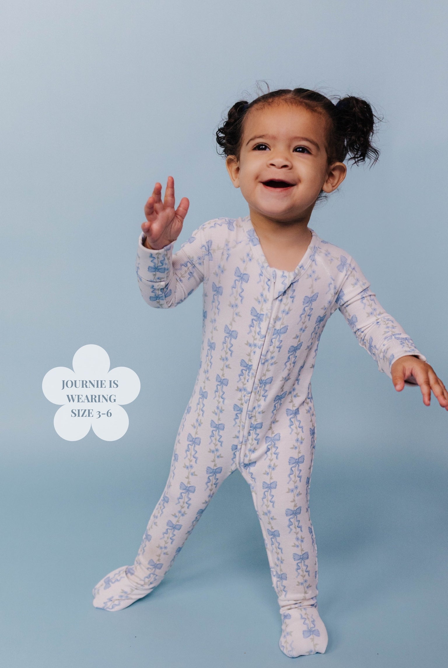 Child wearing a floral onesie on a light blue background