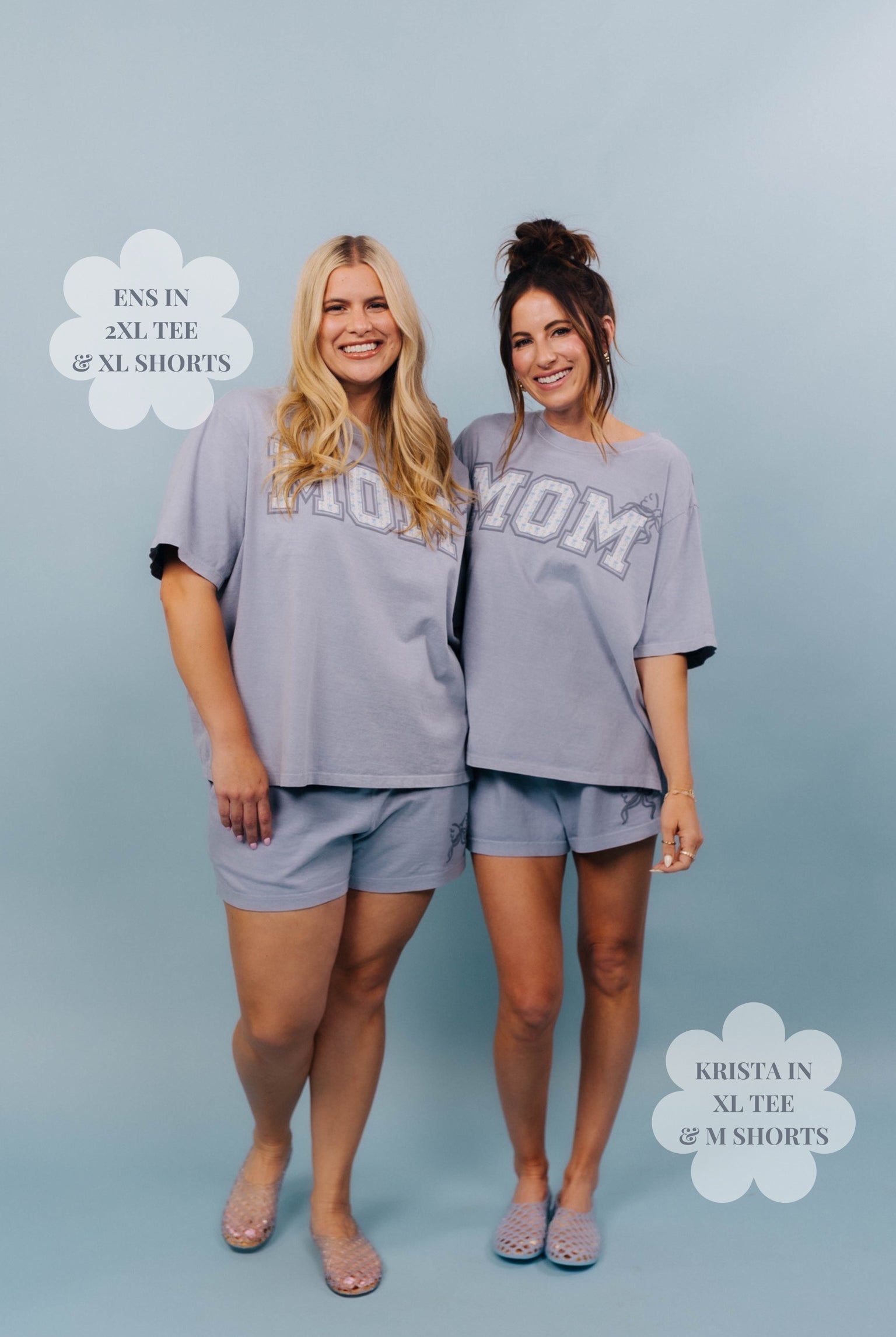 Two women wearing matching blue'MOM' shirts and shorts on a light blue background.