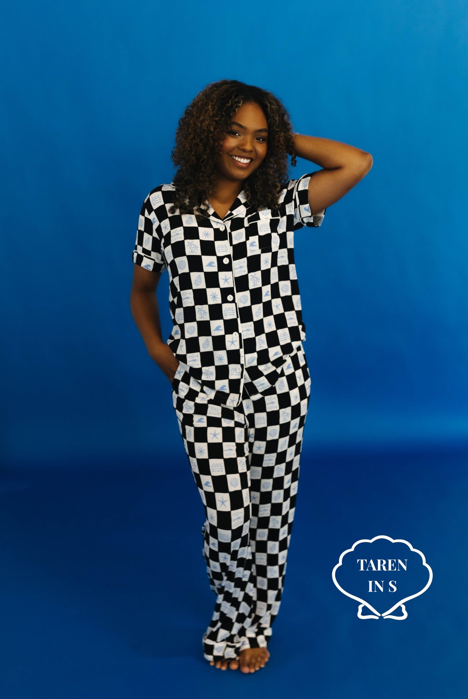 Woman wearing a black and white checkered outfit against a blue background - Taren in S