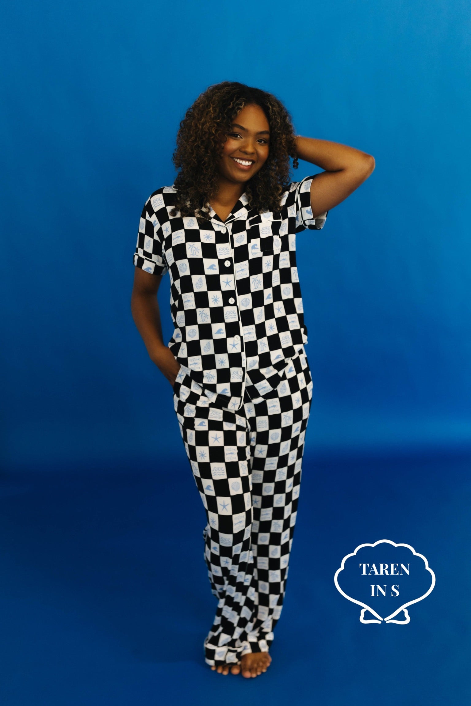 Woman wearing a black and white checkered outfit against a blue background - Taren in S
