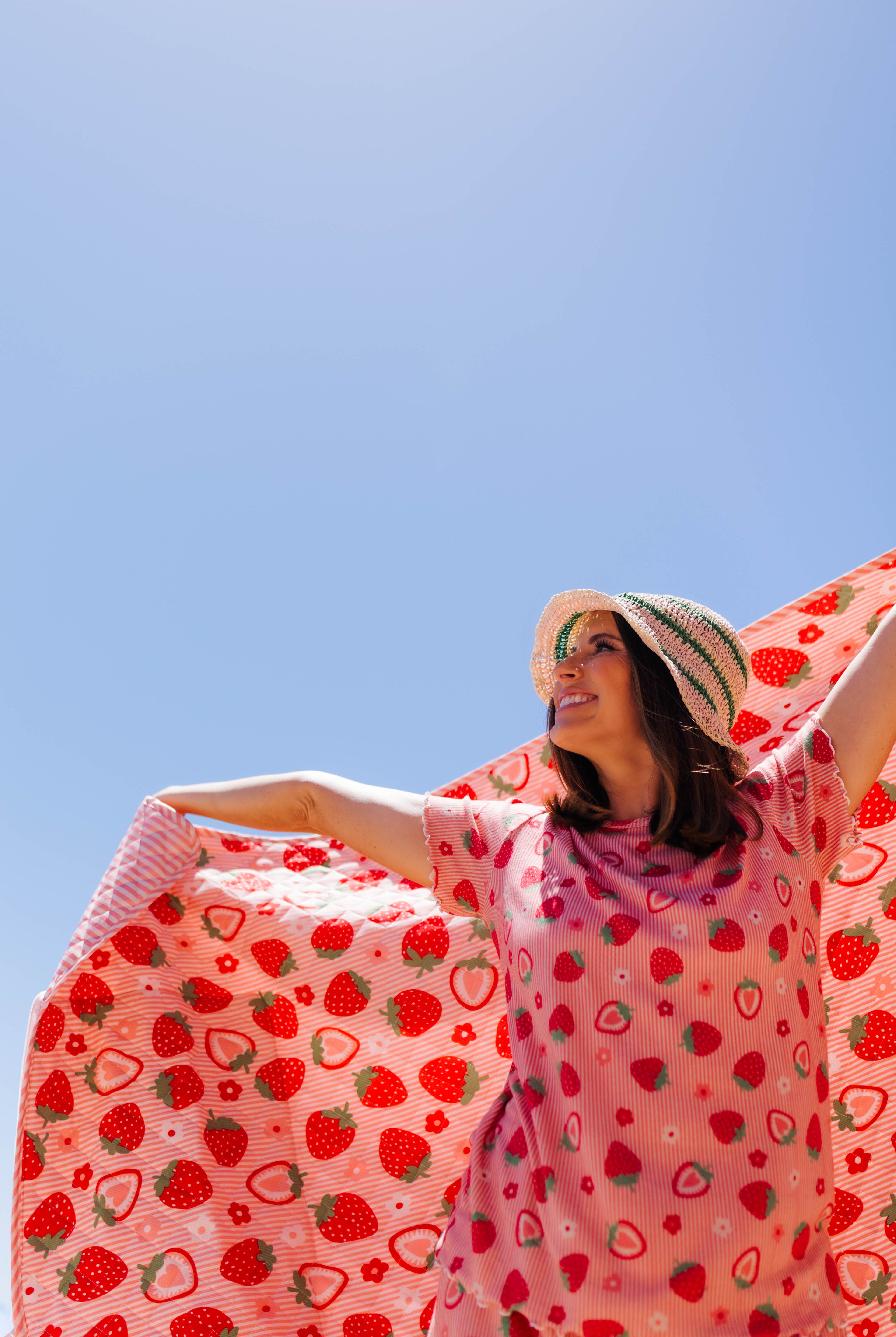 Krista holding the strabwerry outdoor quillow into the air with her matching strawberry pjs