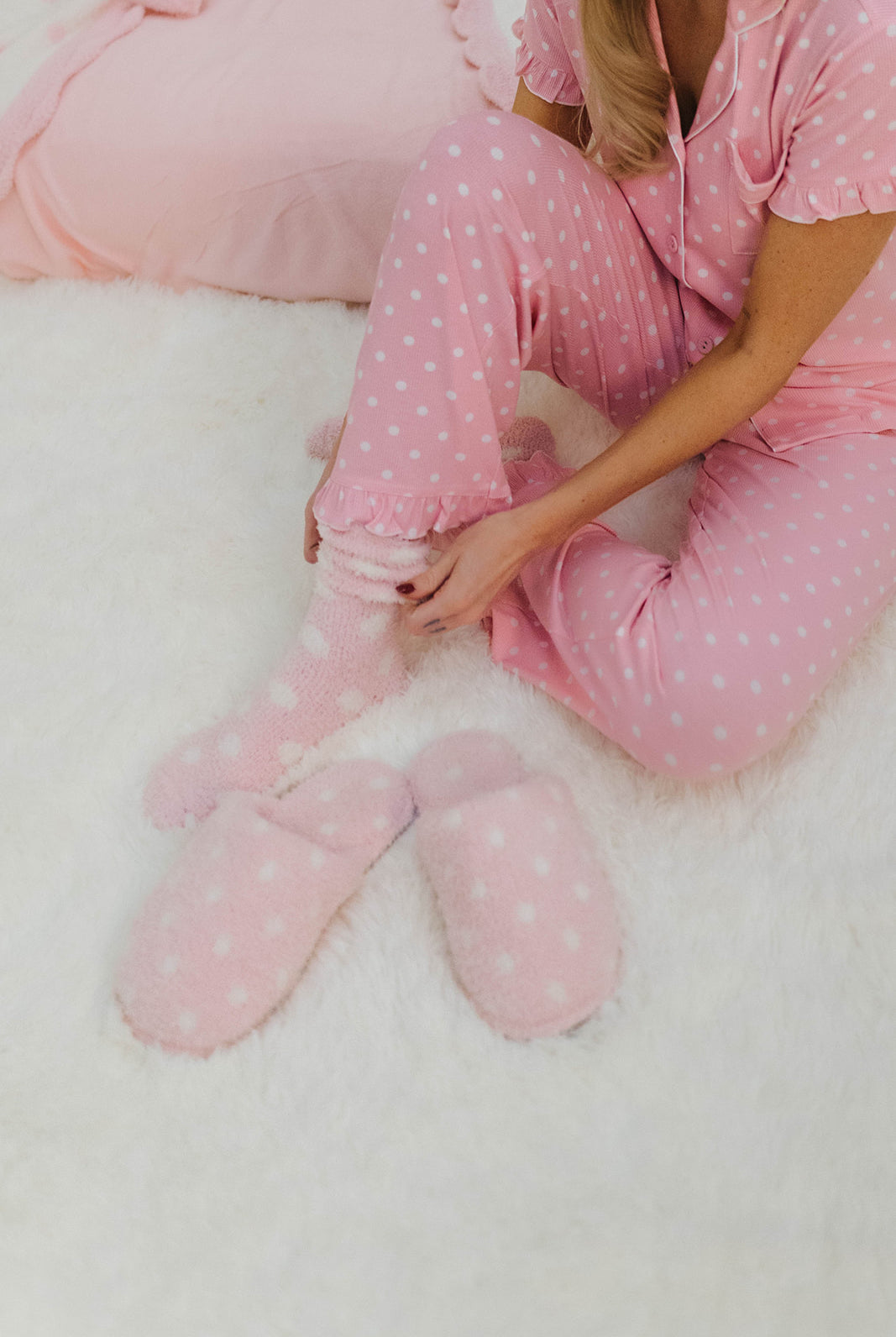 Person wearing pink polka dot pajamas sitting on a white surface.