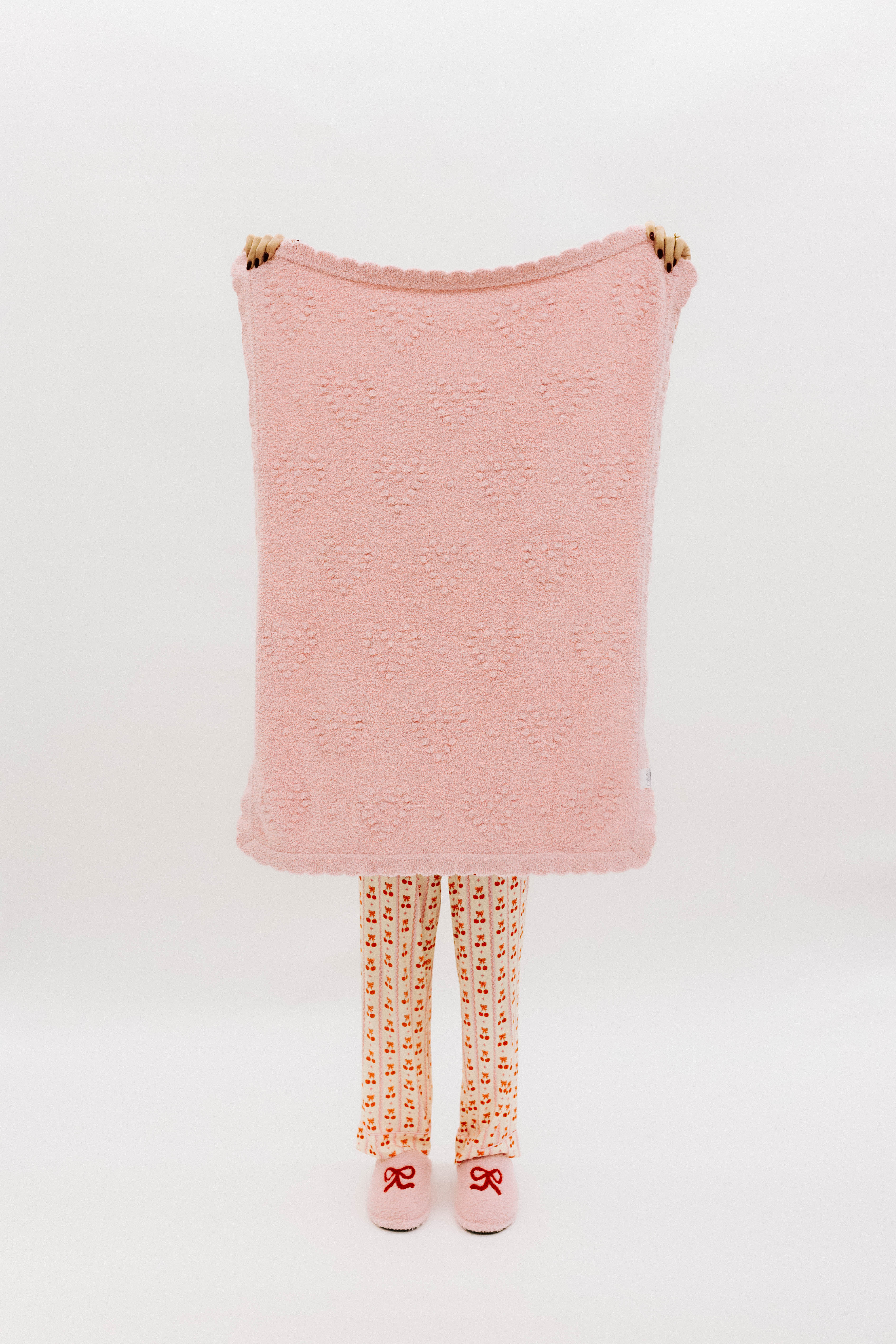 Pink textured blanket held up on white background