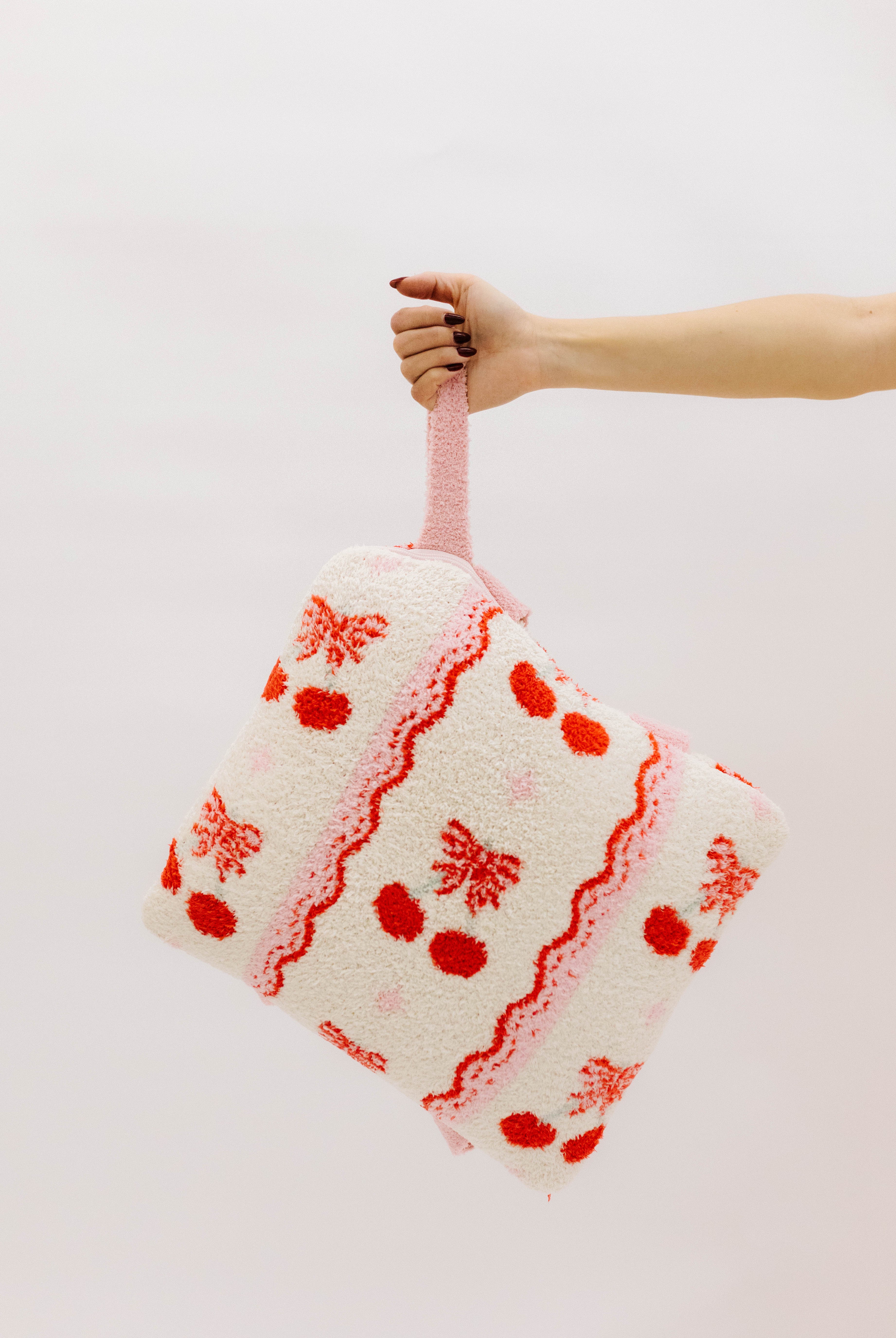 holding the cherry quillow by the wristlet