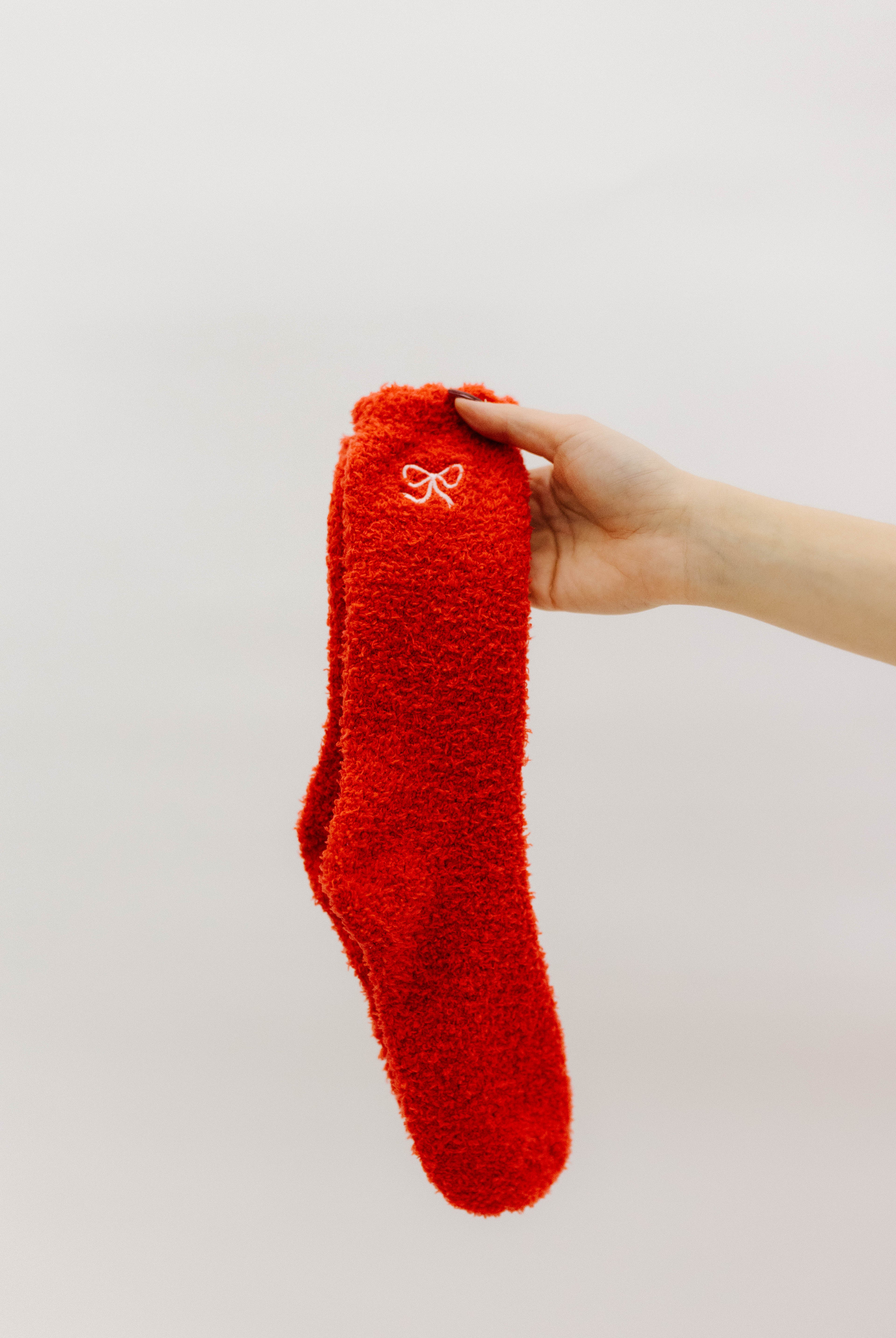 Red fuzzy sock held by a hand against a white background