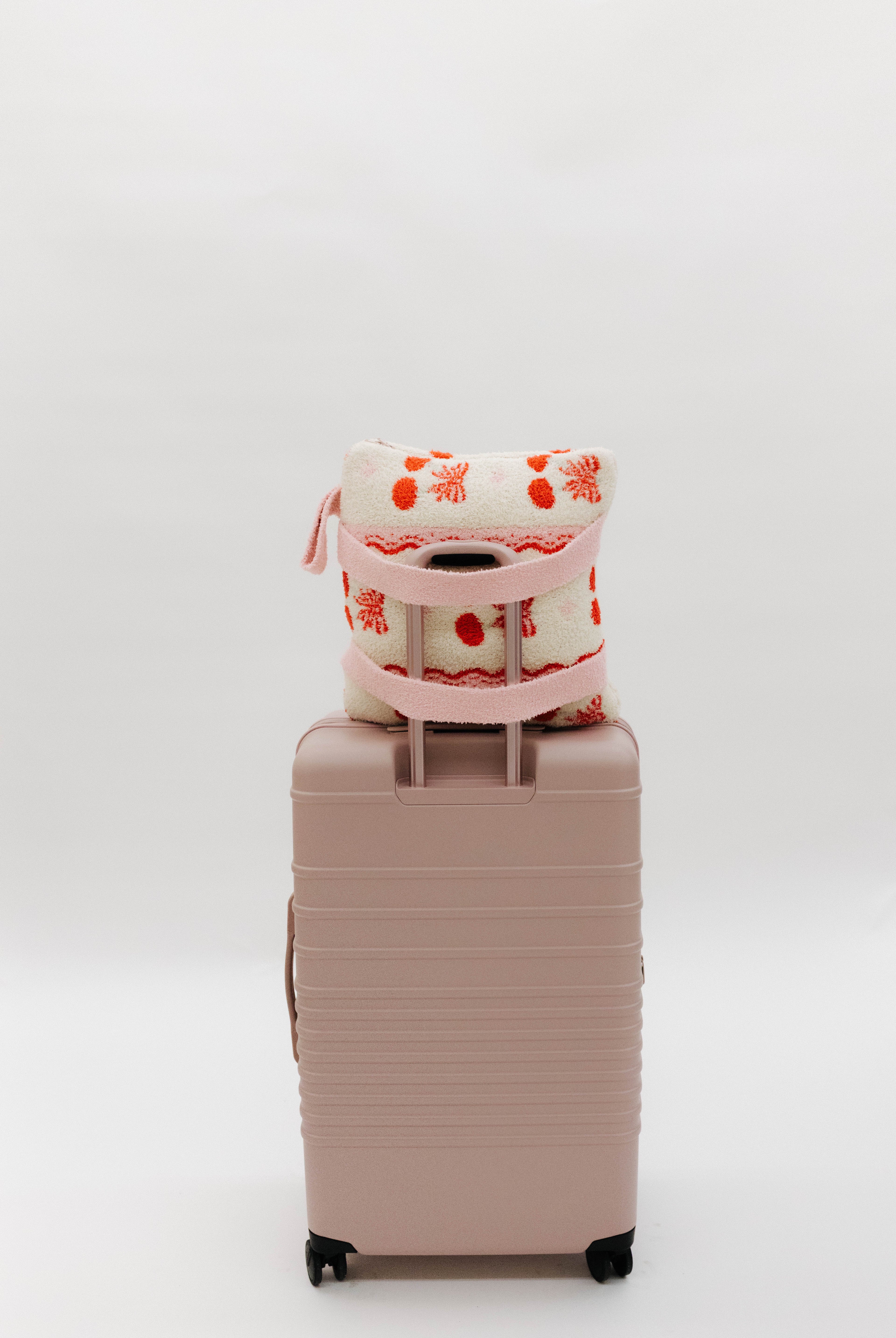 cherry quillow styled on a beis suitcase