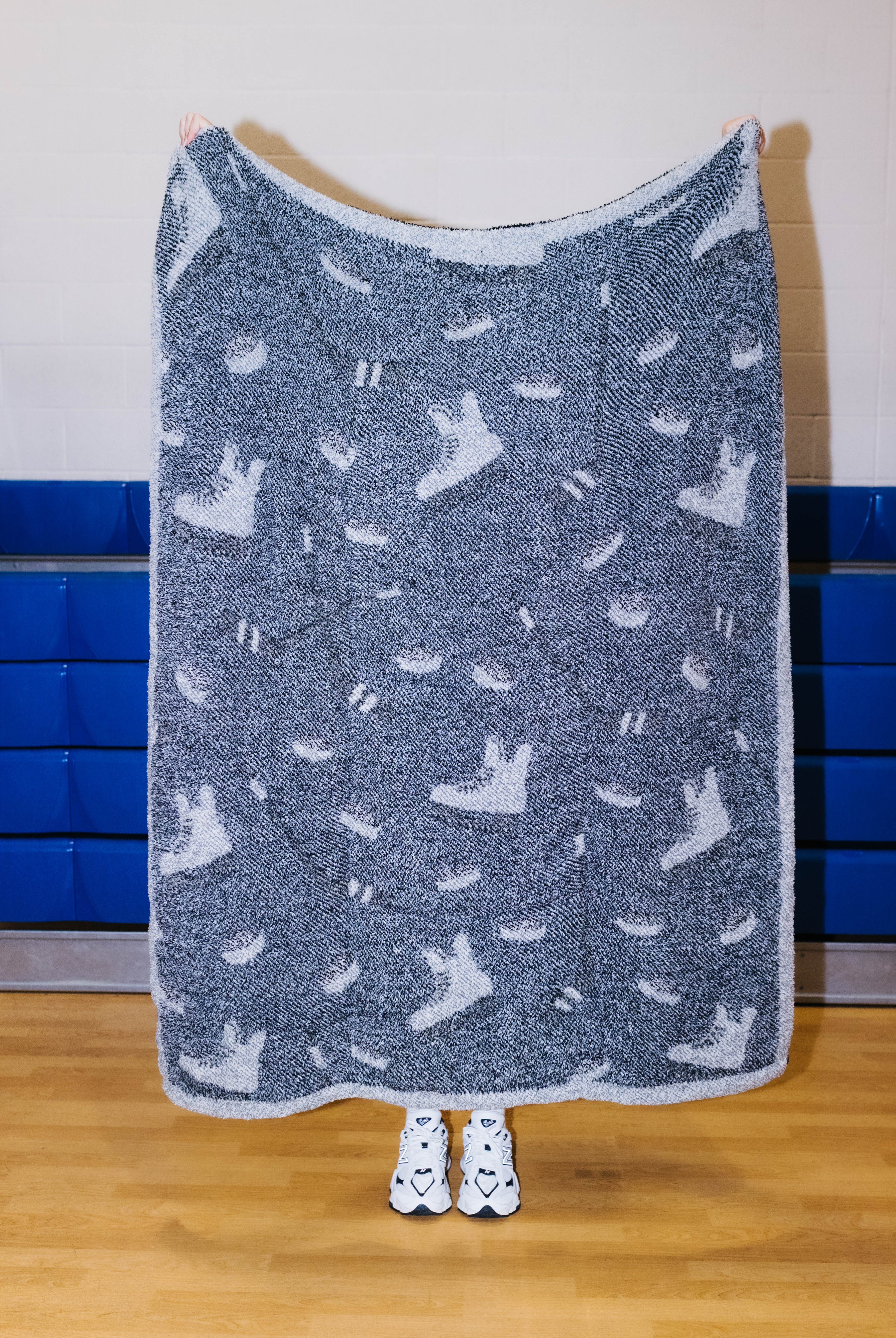 Back side of the hockey blanket being held up showing mostly black background with hockey sillhouetes