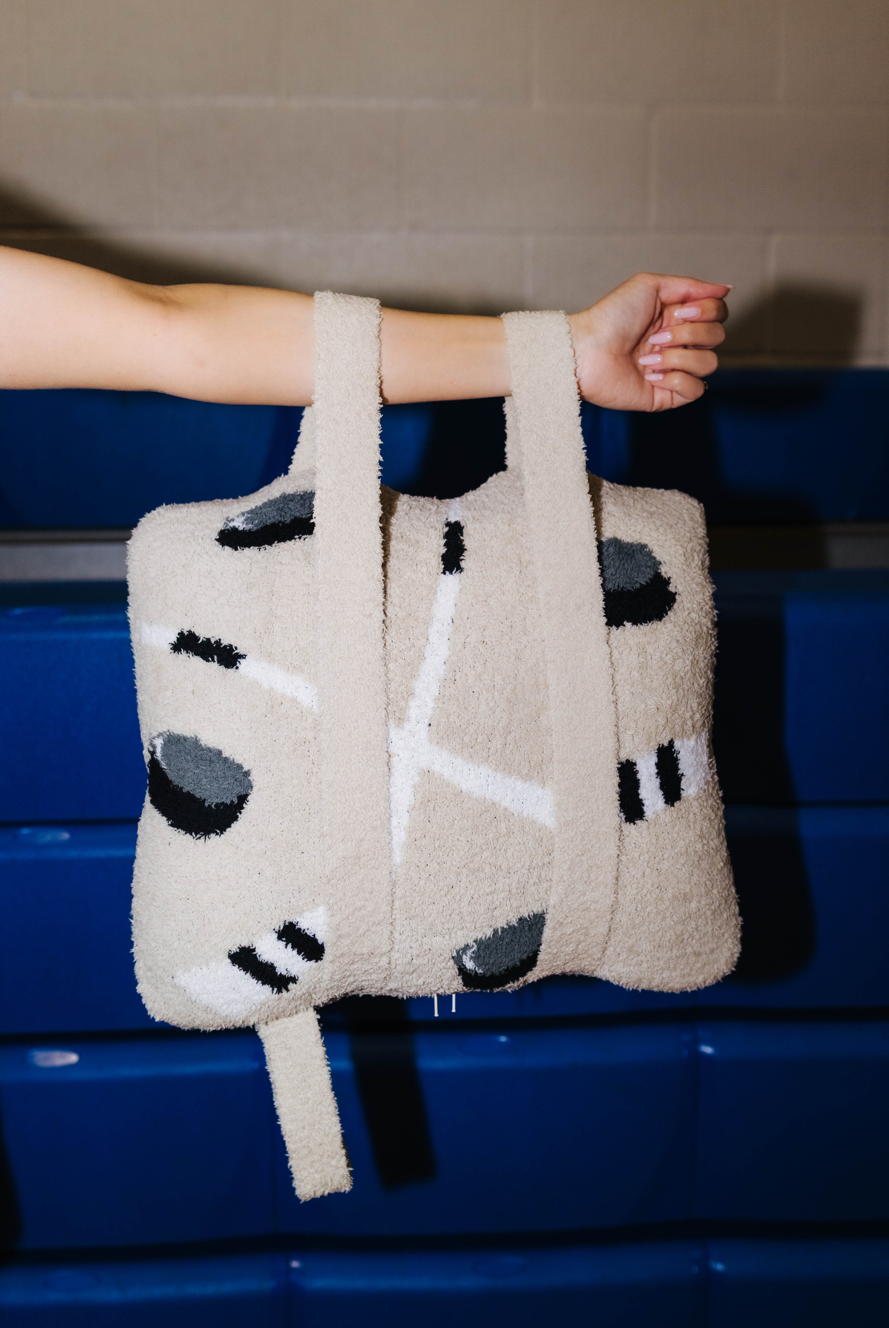 A person's arm and hand holding the quillow by the backpack straps.