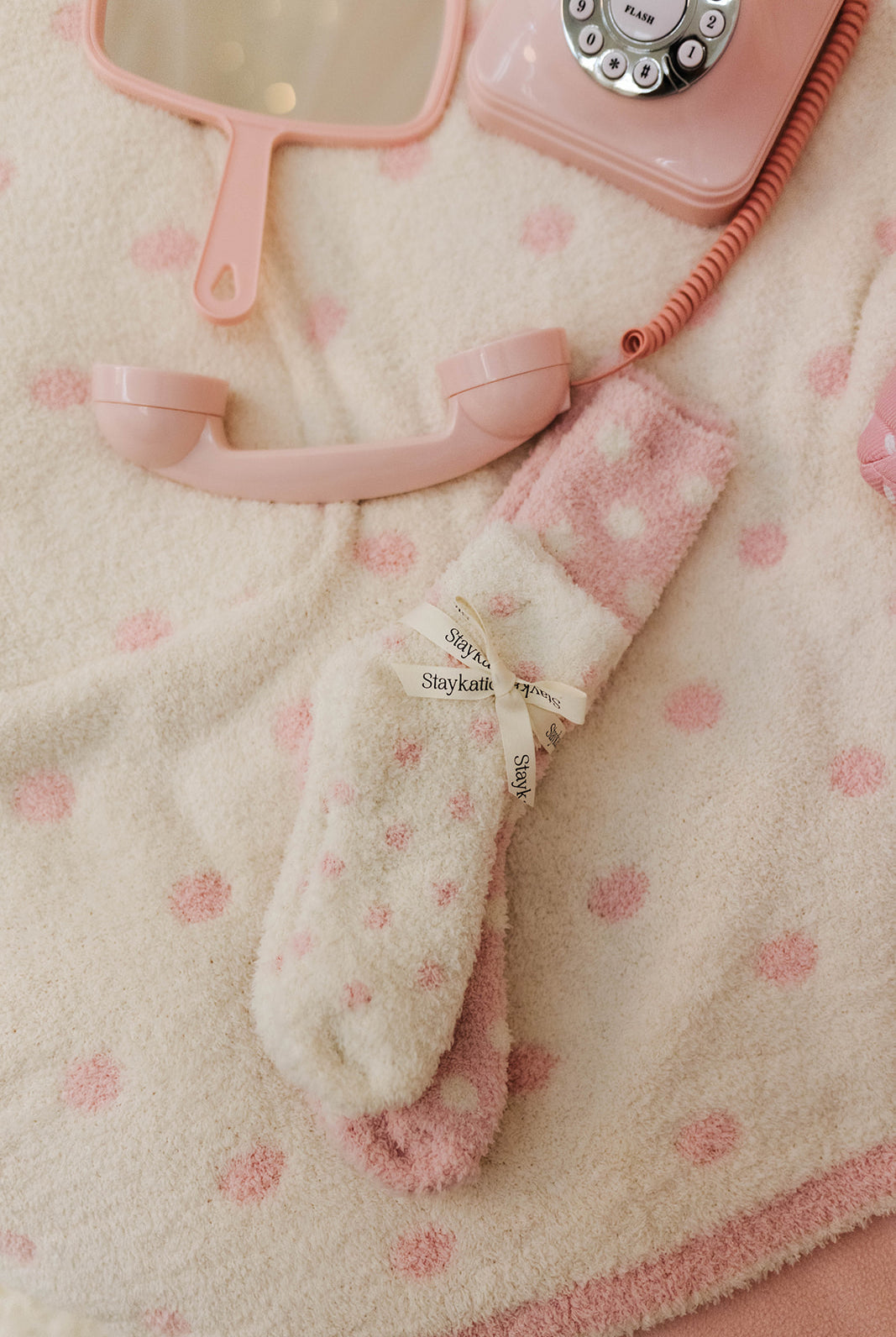 Pink vintage-style phone and matching socks on a textured surface