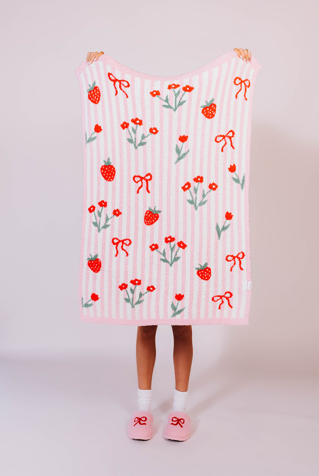 Showing strawberry striped kid blankaet front - holding it up to see details