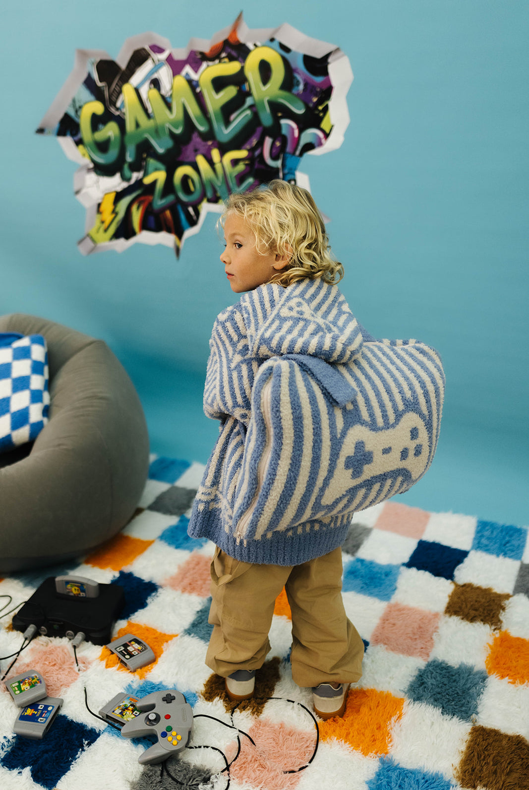 Child with a gaming wearable and backpack in a room with colorful rug and gaming equipment.