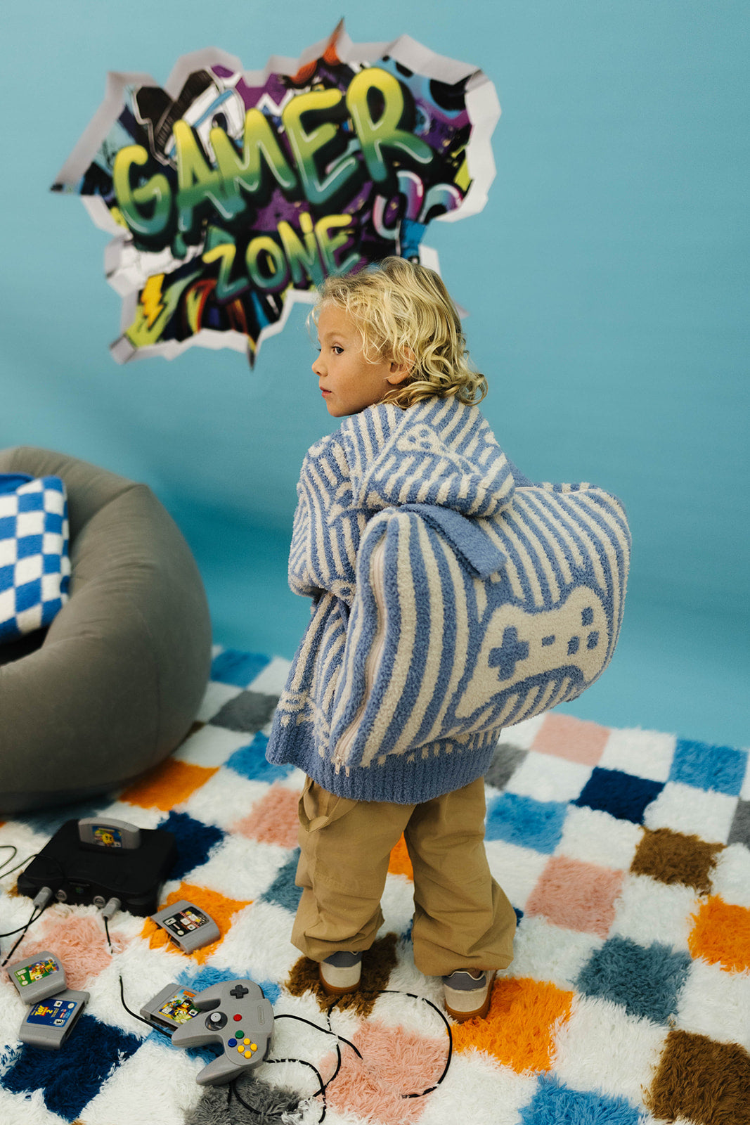 Child with a gaming wearable and backpack in a room with colorful rug and gaming equipment.