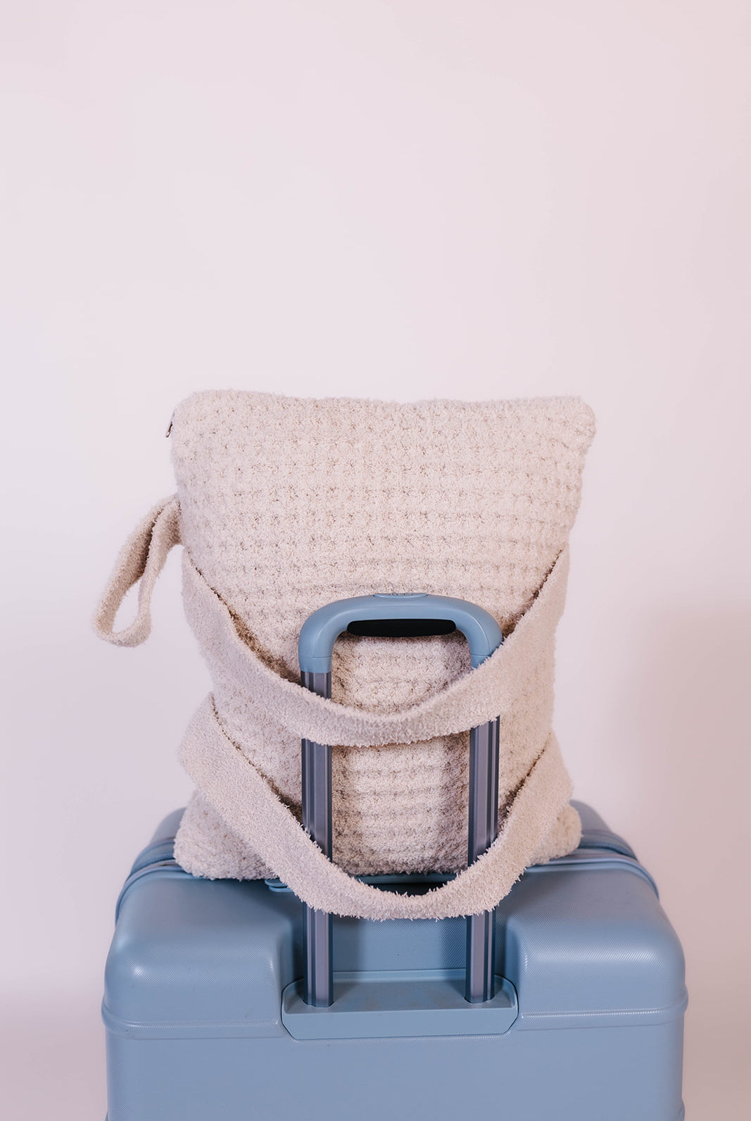 showing the quillow on a suitcase with the straps on the other side