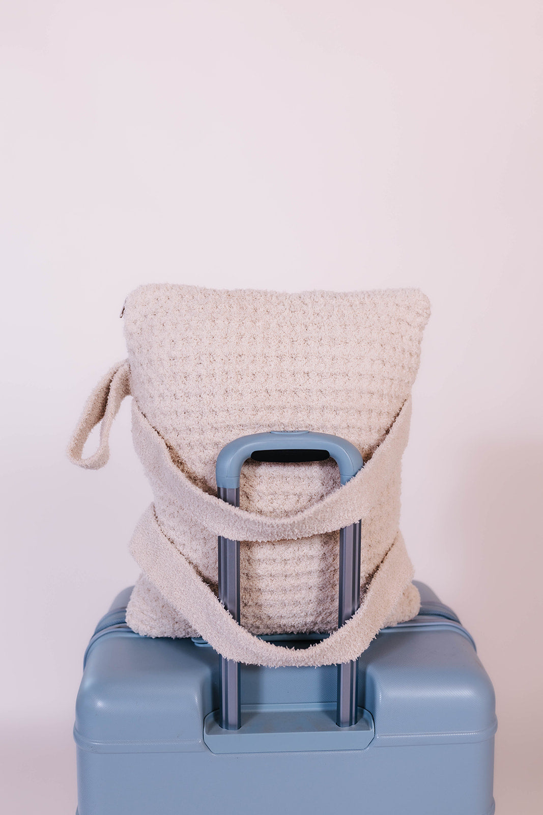 showing the quillow on a suitcase with the straps on the other side