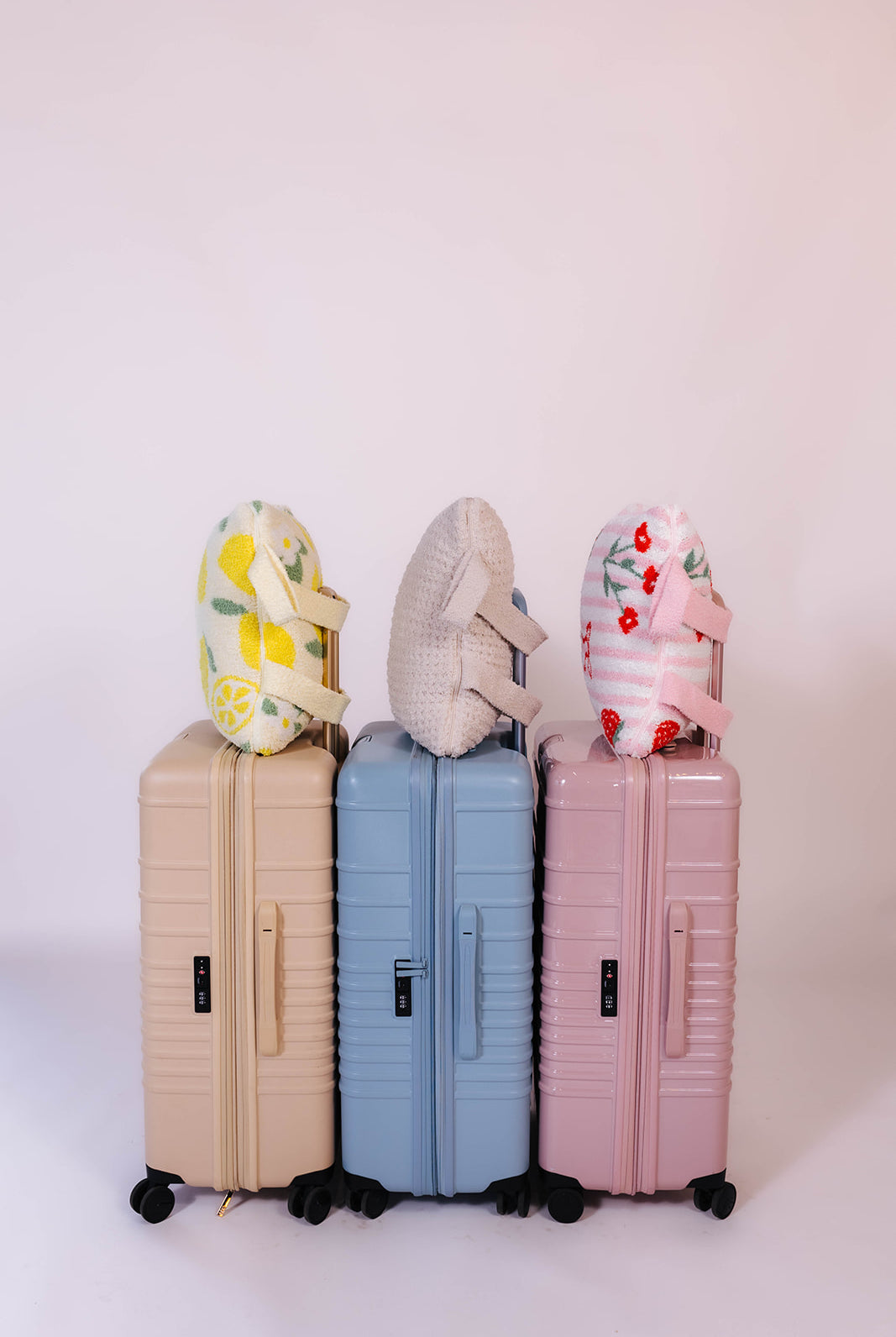 Three suitcases of different colors with the quillows on them