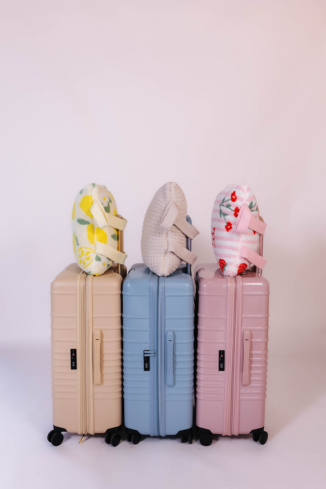 Three suitcases of different colors with the quillows on them