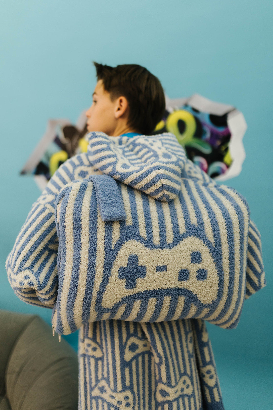 Person wearing a blue and white striped robe with game controller design against a light blue background