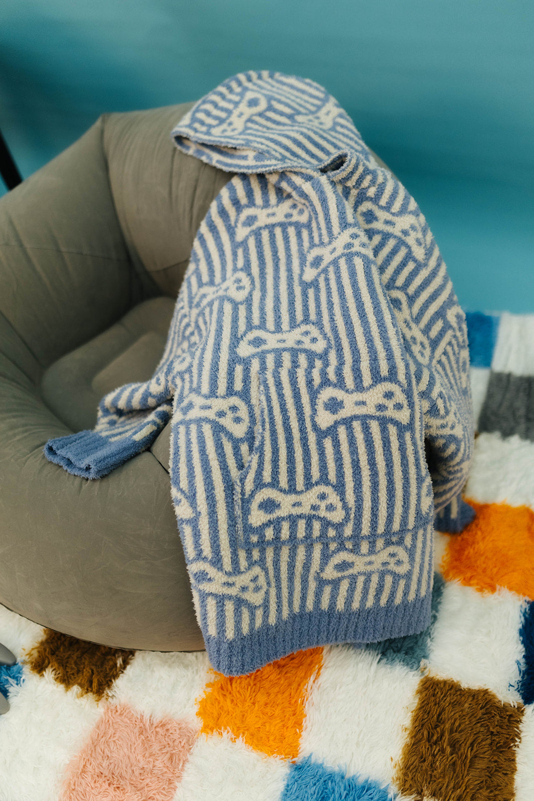 Knitted sweater with game pattern draped over a chair on a colorful rug
