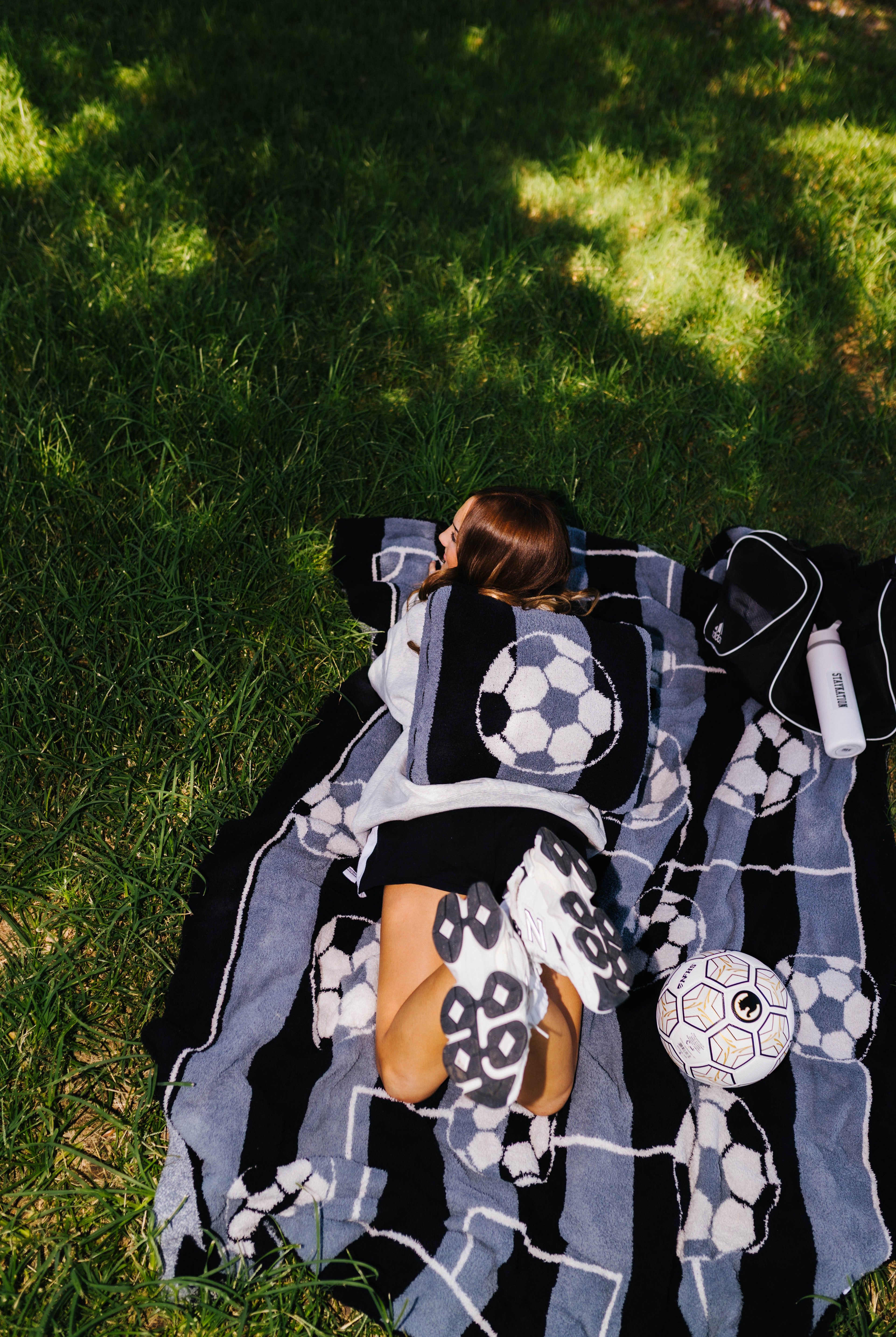 girl laying on the soccer ball blanket with a soccer ball quillow on her back