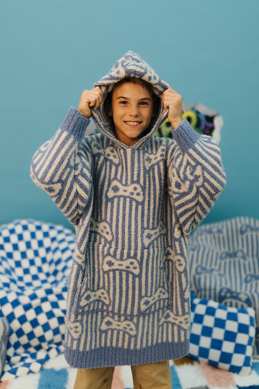 Child wearing a blue and white patterned sweater with a hood against a blue background.