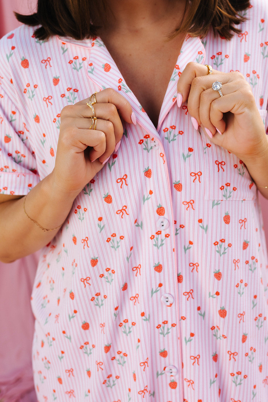 Person wearing a pink floral patterned pajama top with their hands on the collar.