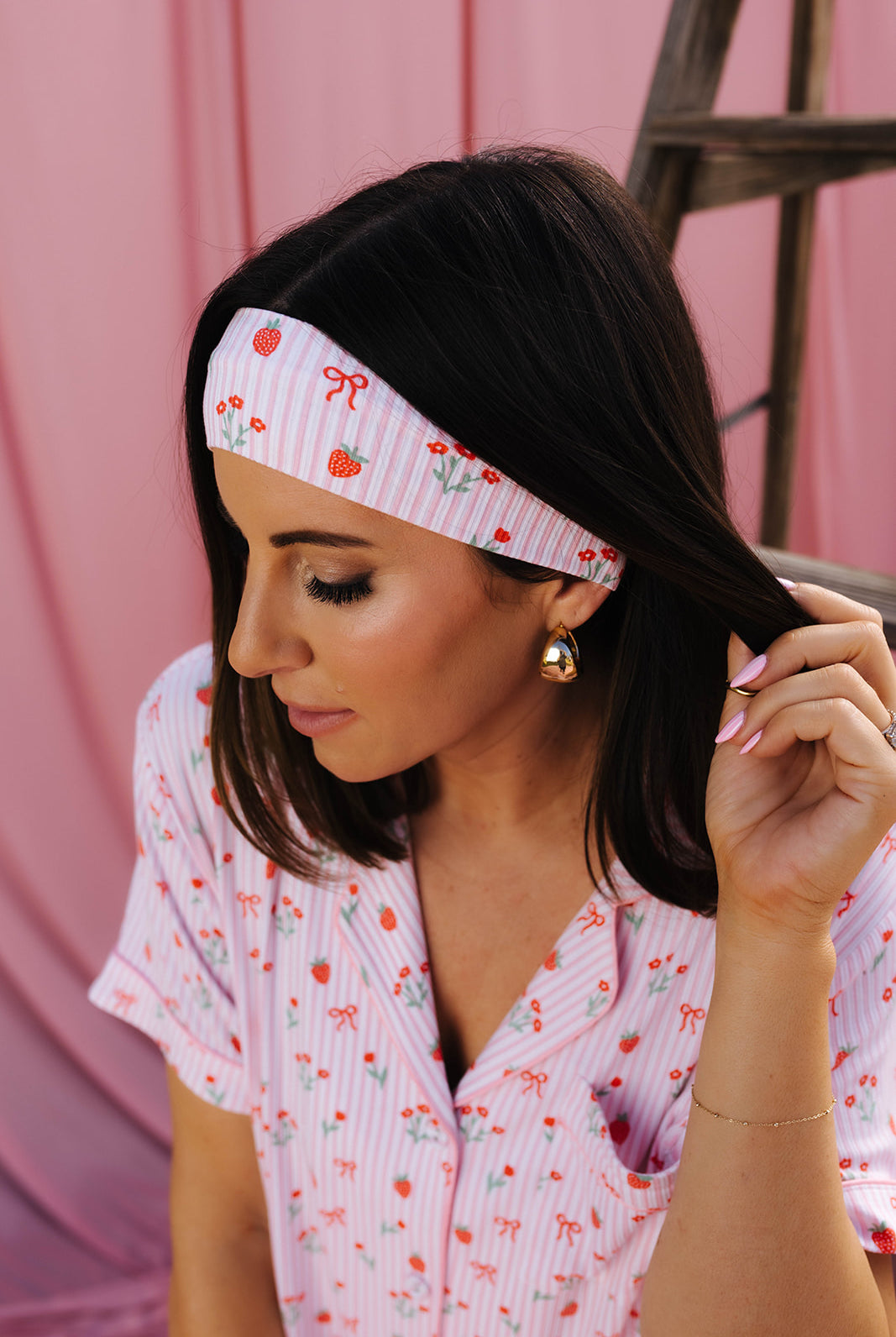 Woman wearing a pink floral headband and matching outfit against a pink background