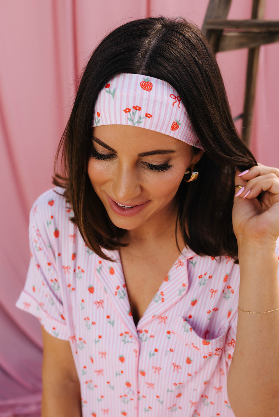 Woman wearing a pink floral headband and matching outfit against a pink background