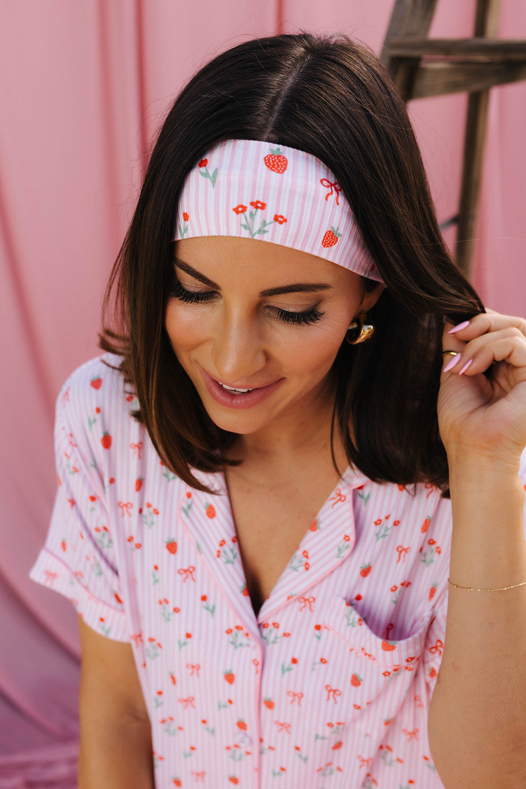 Woman wearing a pink floral headband and matching outfit against a pink background