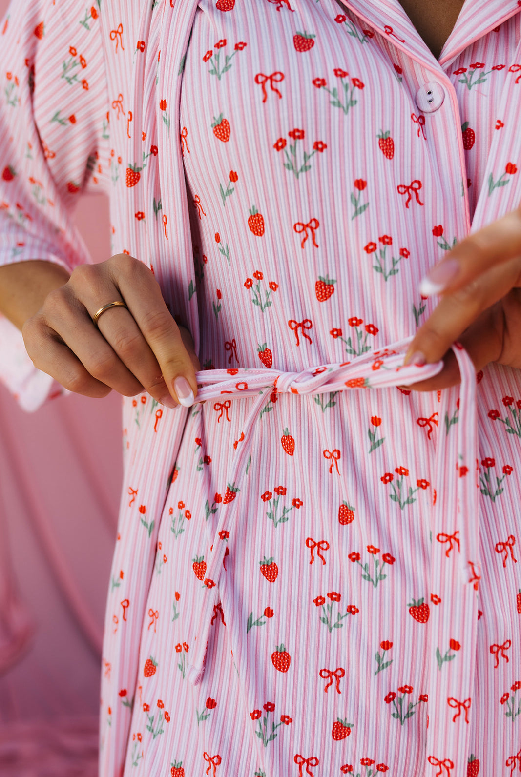 Close-up of a person wearing a pink robe with red strawberry and green leaf pattern.
