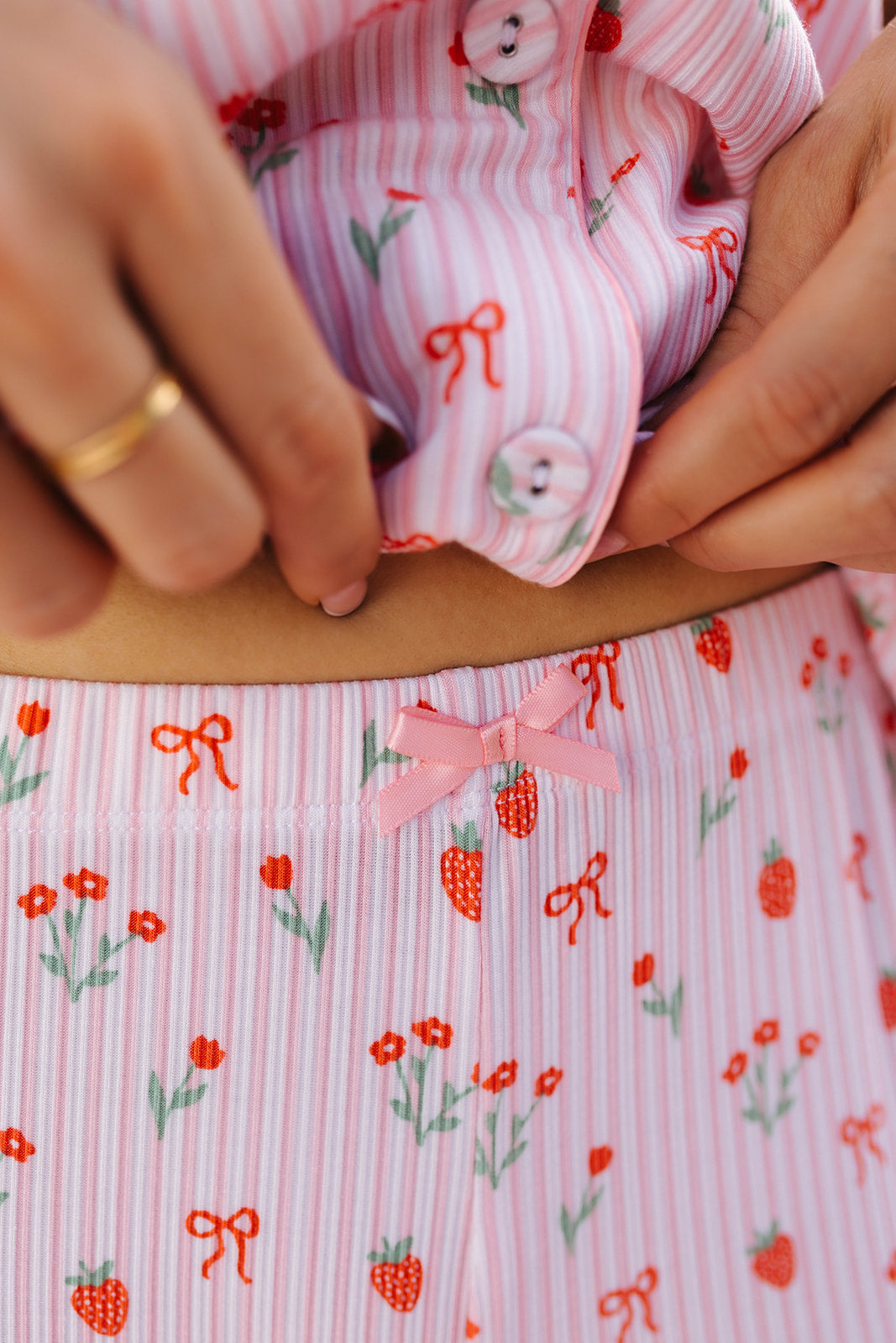 Close-up of hands showing a pink fabric with floral and bow patterns.