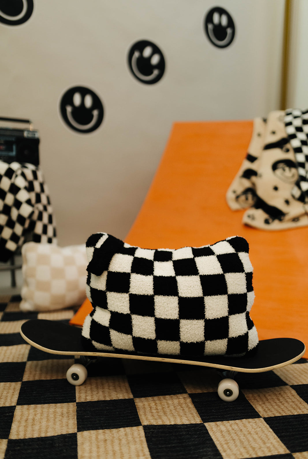 Checkered pillow on a skateboard with a checkered floor and wall decorations in the background