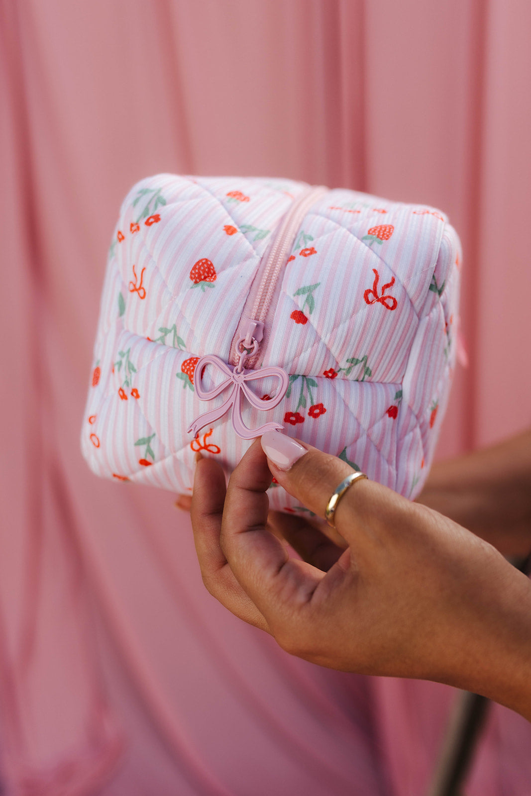 hand holding the bow of the cosmetic bag zupper