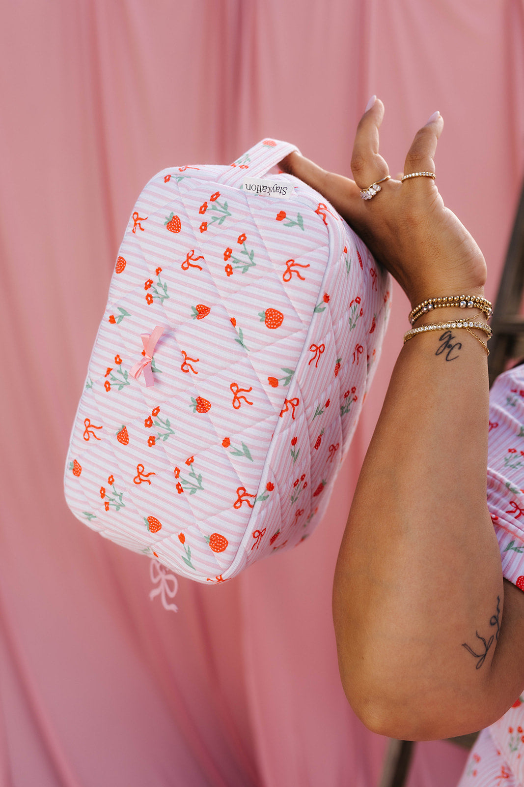 person holding strawberry stripe printed cosmetic bag