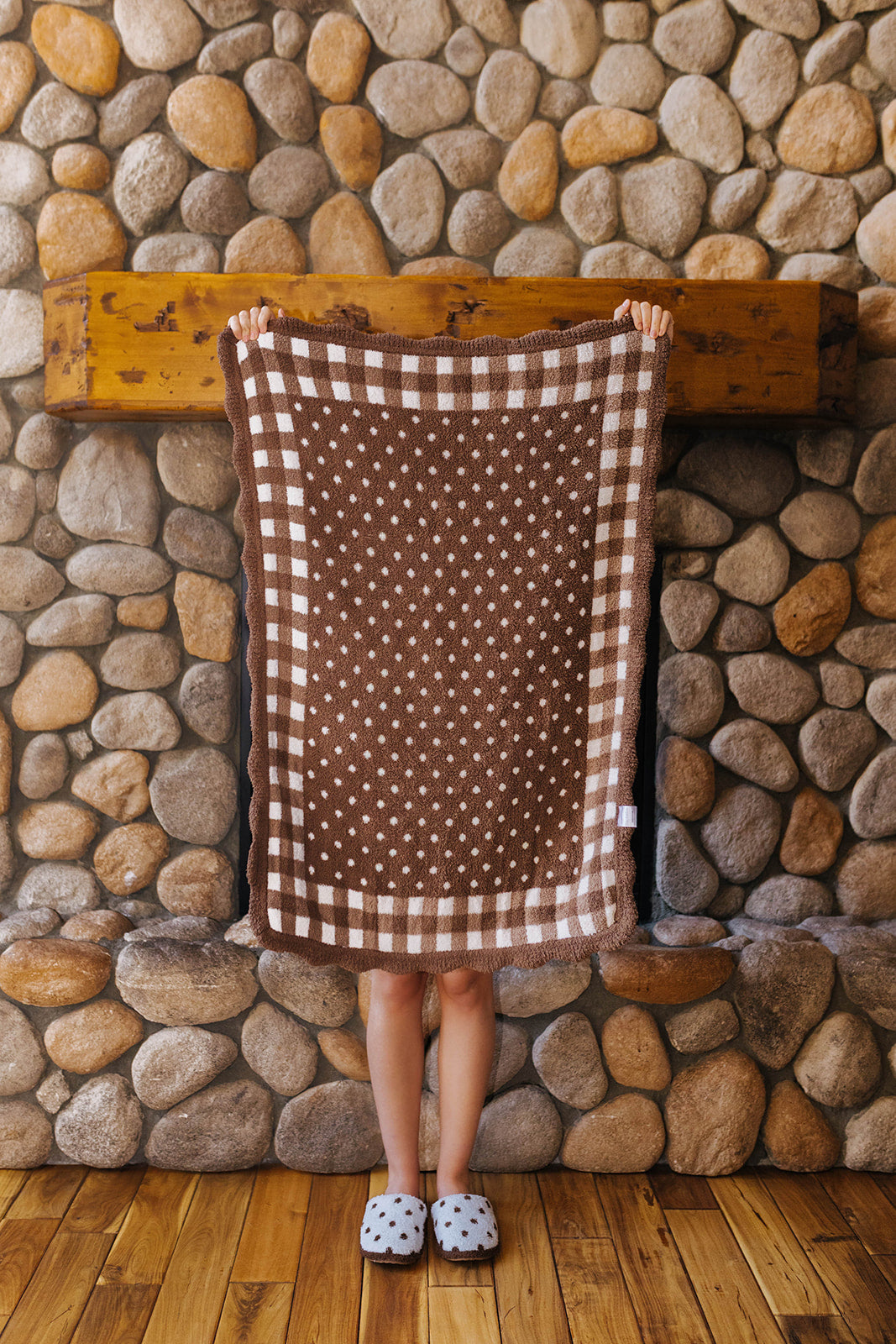 Brown kids blanket with white polka dots and a gingham border held open.