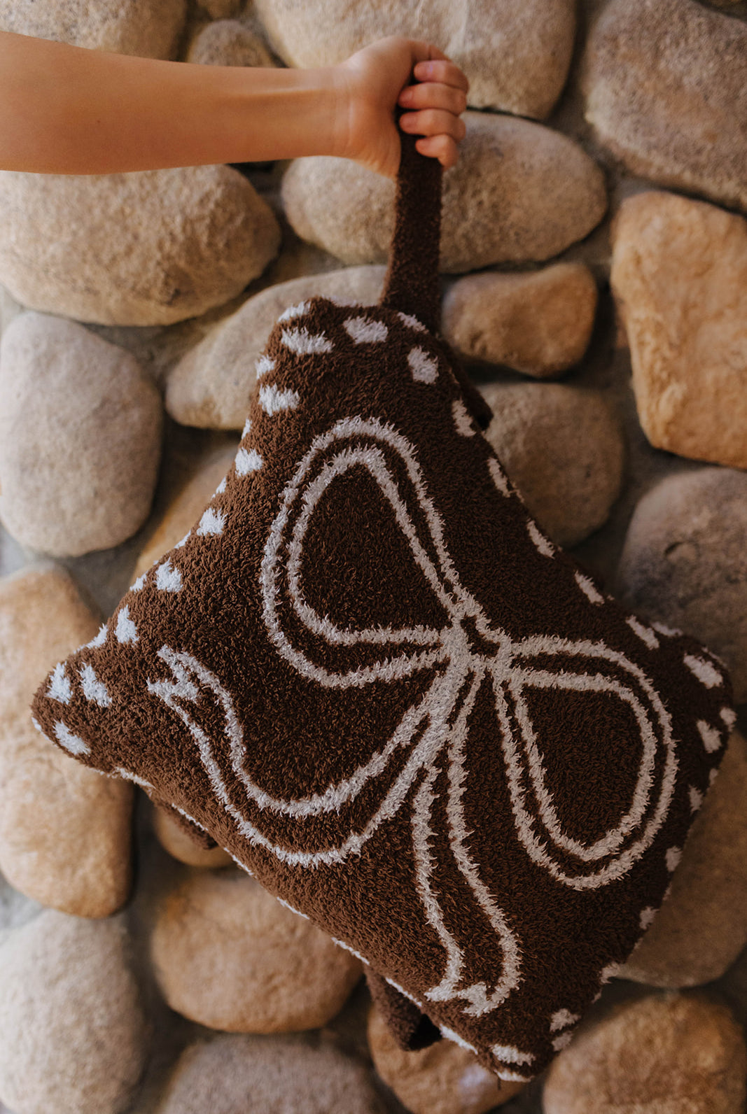 Bow quillow folded into a pillow and held by its wrist strap.